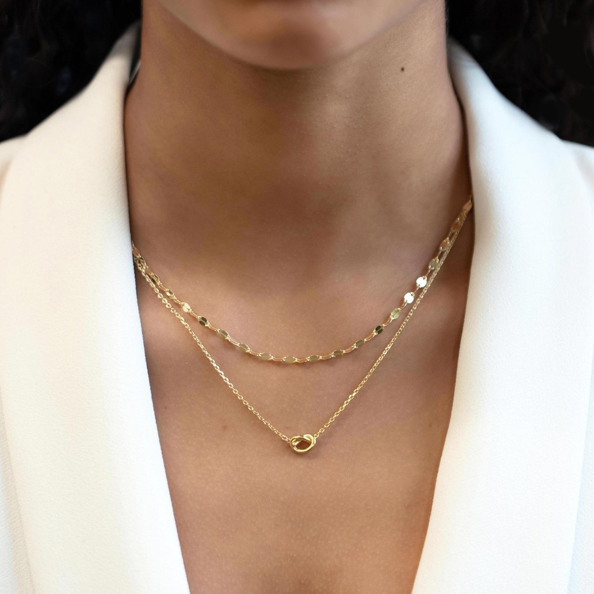 Gold vermeil mirror-link chain necklace layered with a knotted-pendant chain, shown on a model's neckline