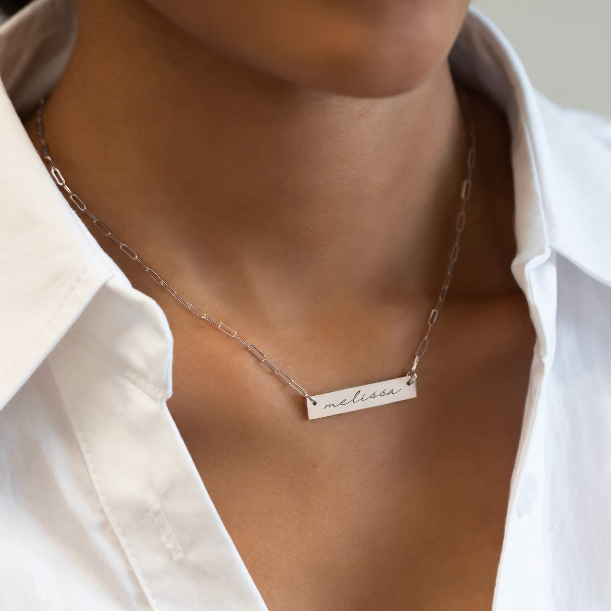 Sterling silver engravable bar necklace engraved with a name, shown on a model's neckline