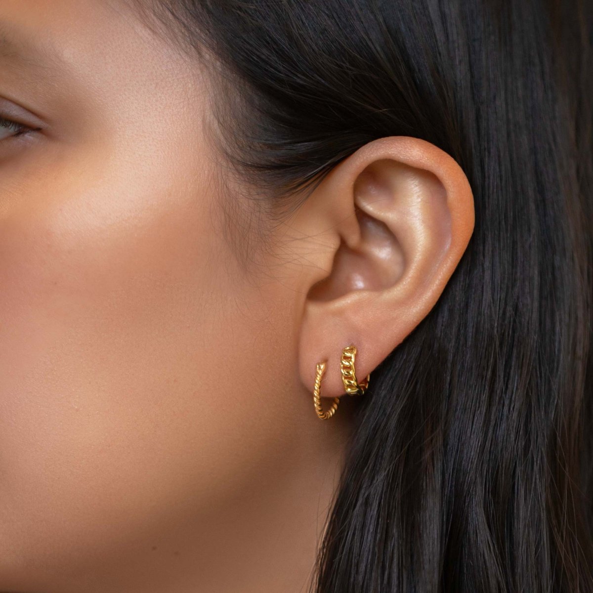 Gold vermeil chain link huggie hoops shown on a model's lobe in a stack of two hoops