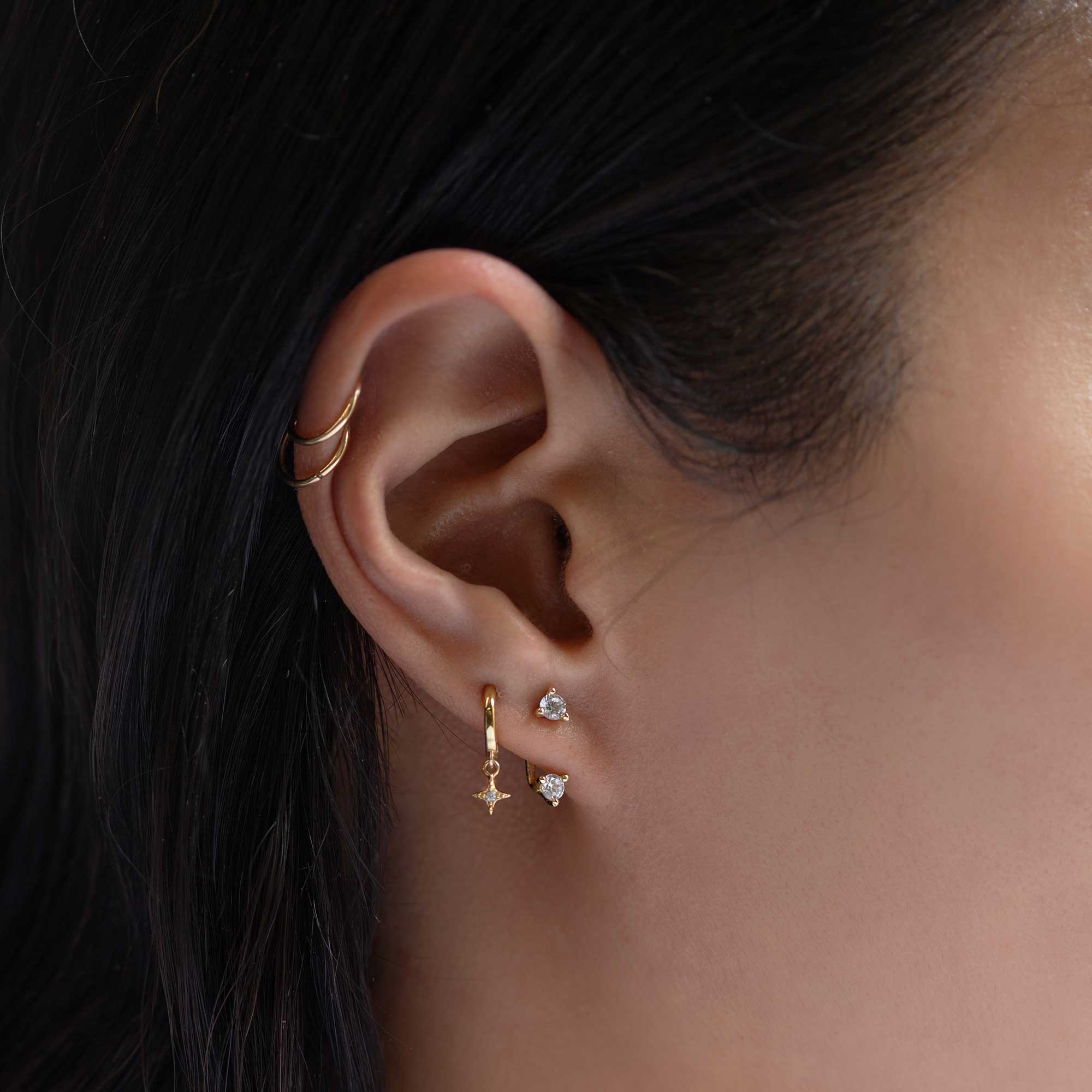 Gold vermeil white zirconia solitaire stud paired with a star-drop huggie, shown on a model's lobe