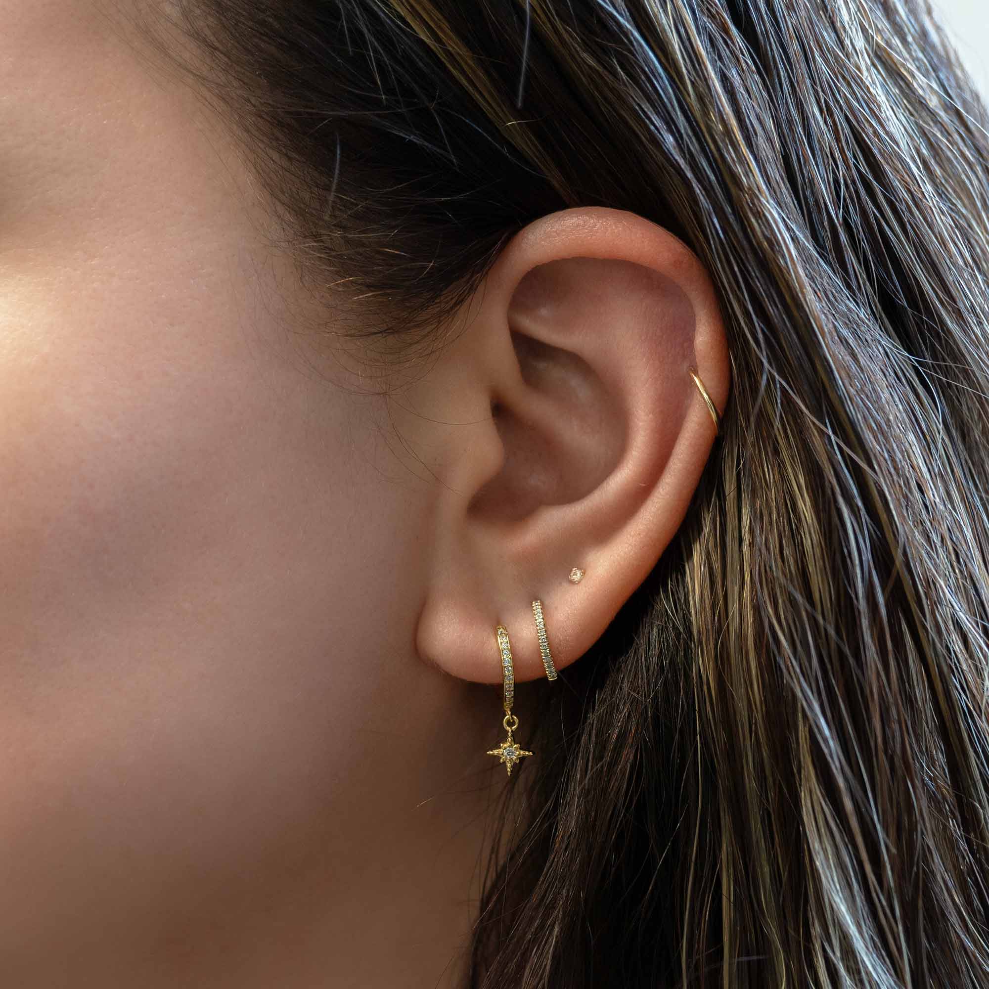 Gold vermeil starburst drop huggie hoop shown on a model's lobe