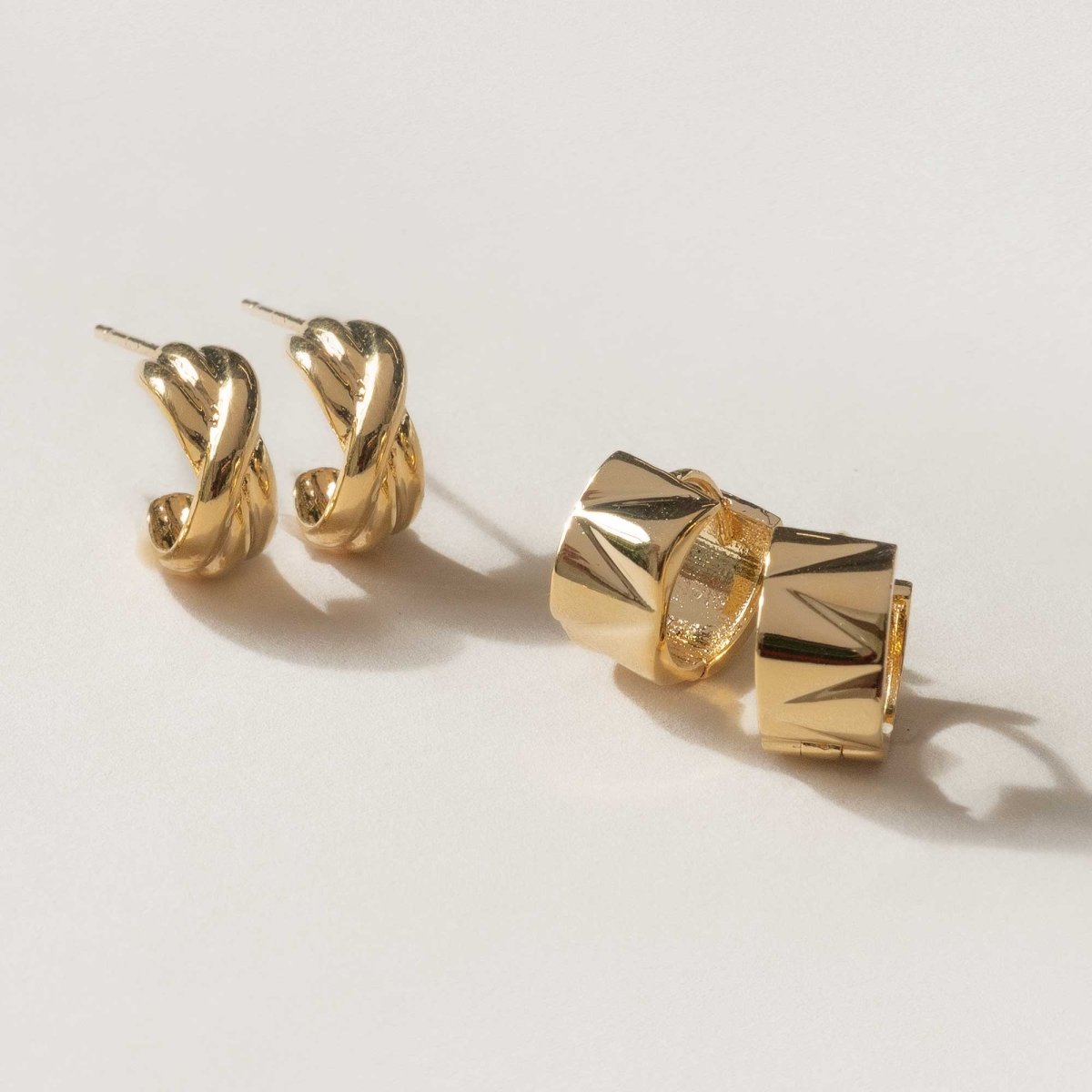 Gold vermeil twisted criss-cross huggie hoops shown front and side on a cream background
