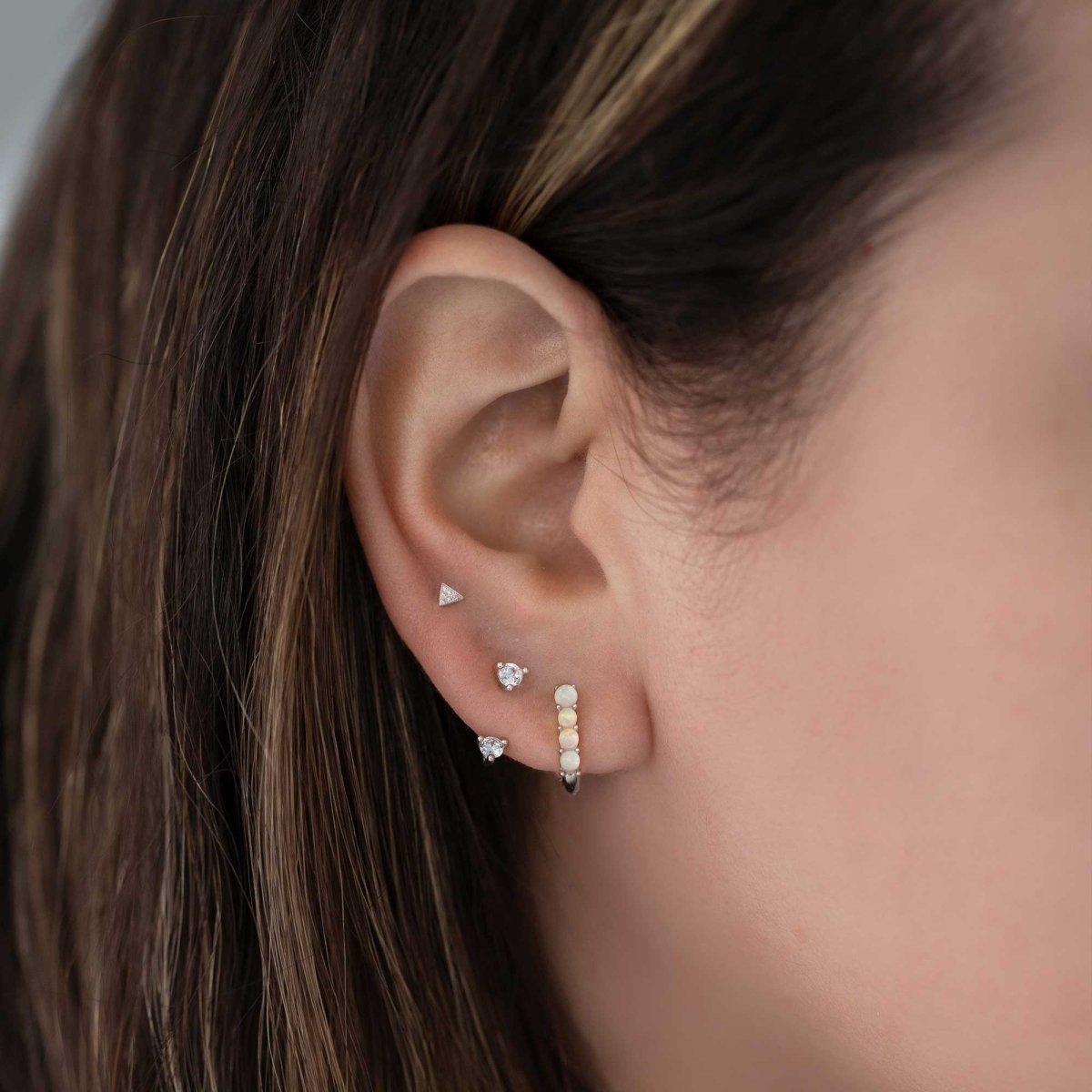 14K white gold pavé triangle stud with clear stones, shown on a model's lobe in an ear stack
