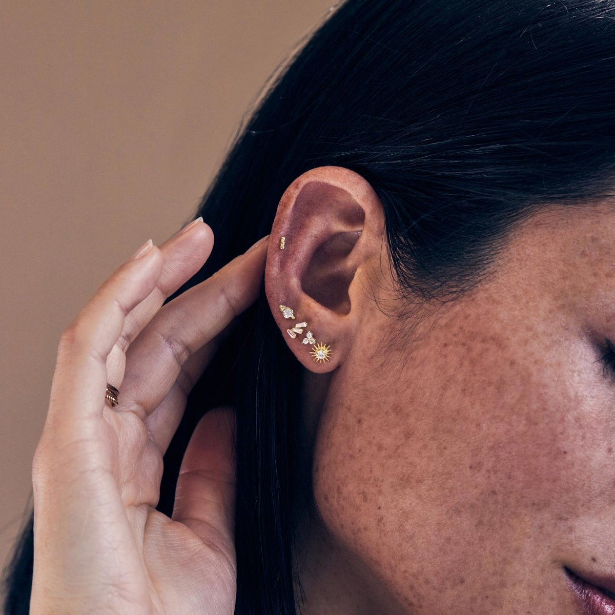Gold titanium beaded bar flat back stud shown in a stud stack on a model's ear