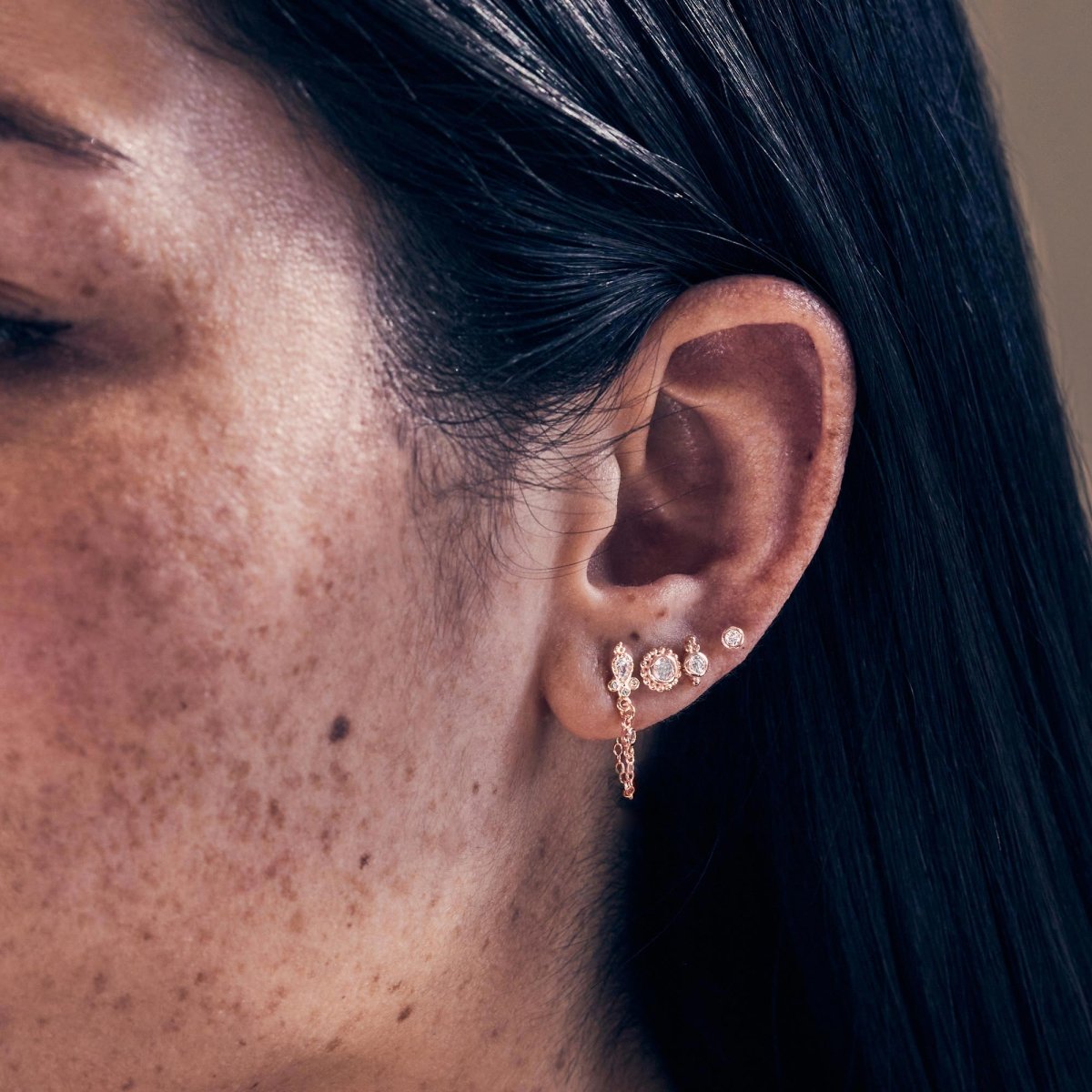 Rose gold vermeil chain stud earrings with clear stones, shown across stacked lobe piercings
