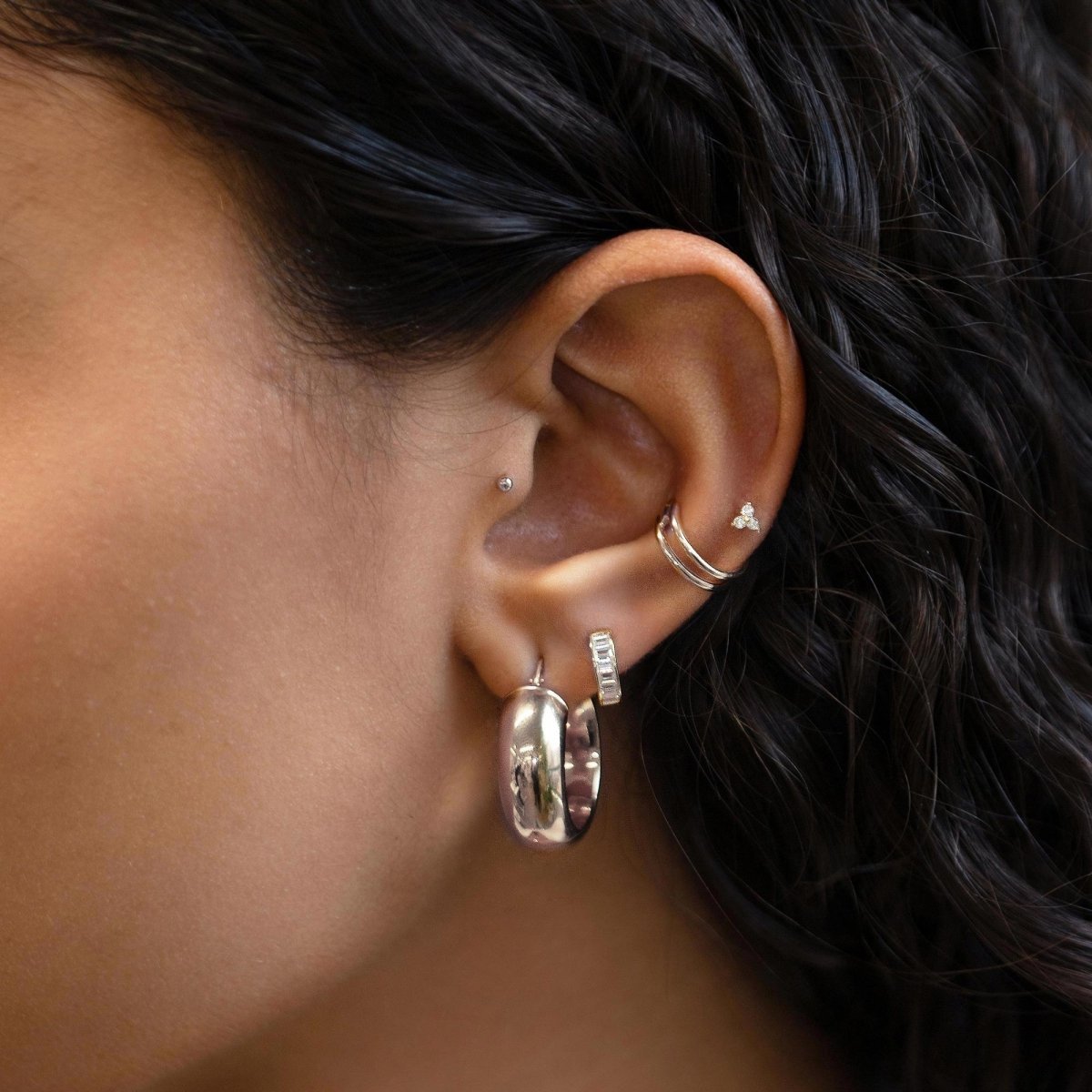 Close up of woman's ear featuring 14K White Gold Tiny Clover Pave Stud and chunky hoop earring 
