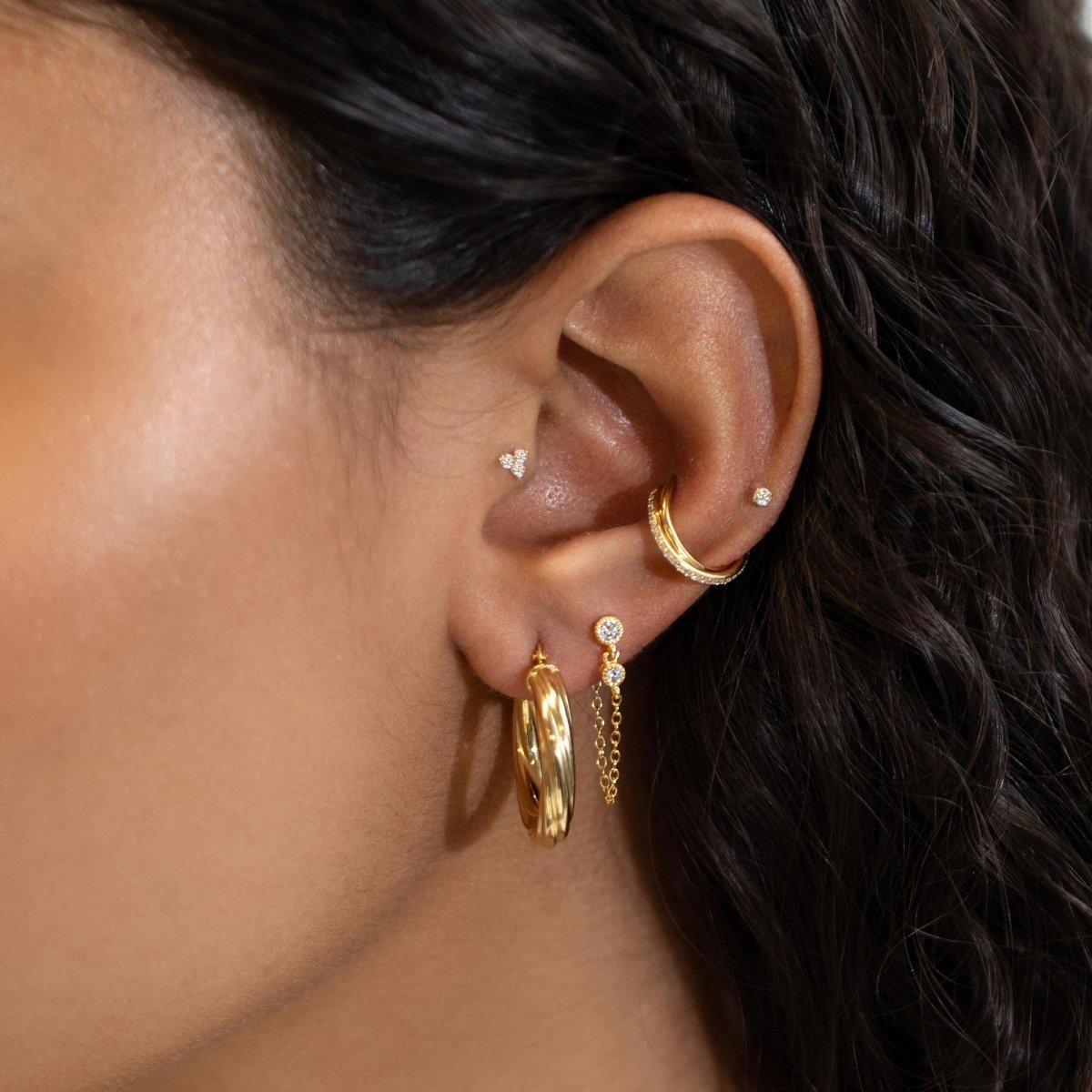 Gold vermeil white zirconia bezel chain earring with a looping chain, styled in an ear stack on a model