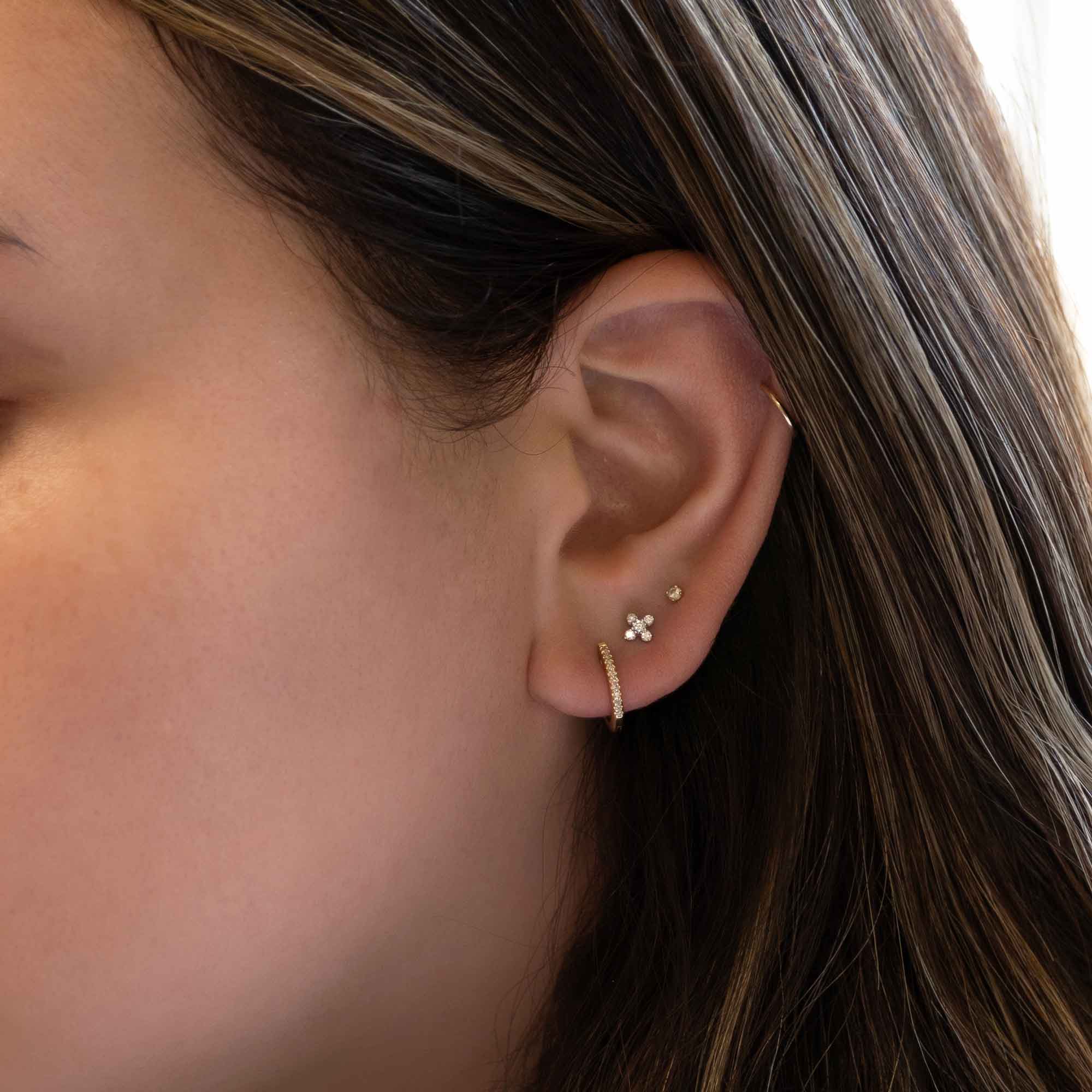 14K gold diamond fleur stud shown on a model's lobe with a thin pavé hoop