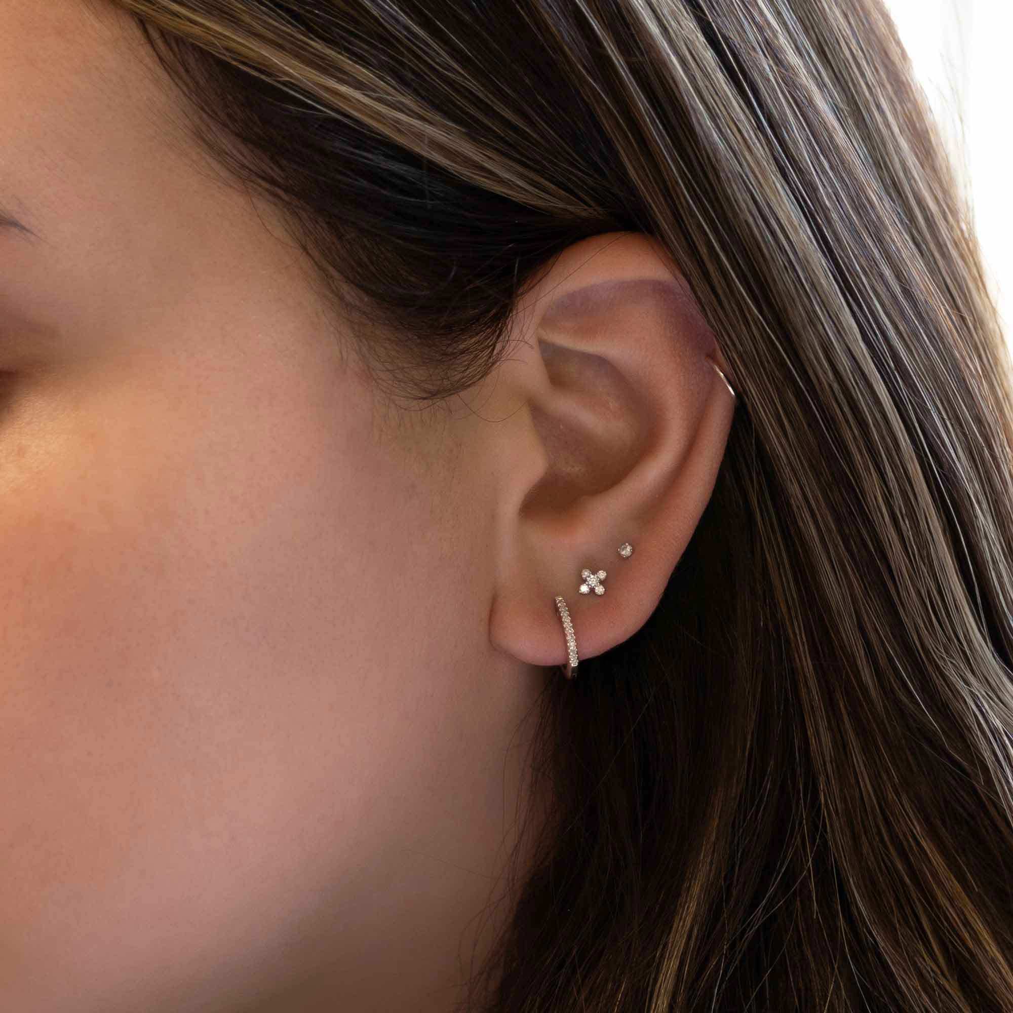 14K white gold diamond fleur stud shown on a model's lobe above a pavé hoop