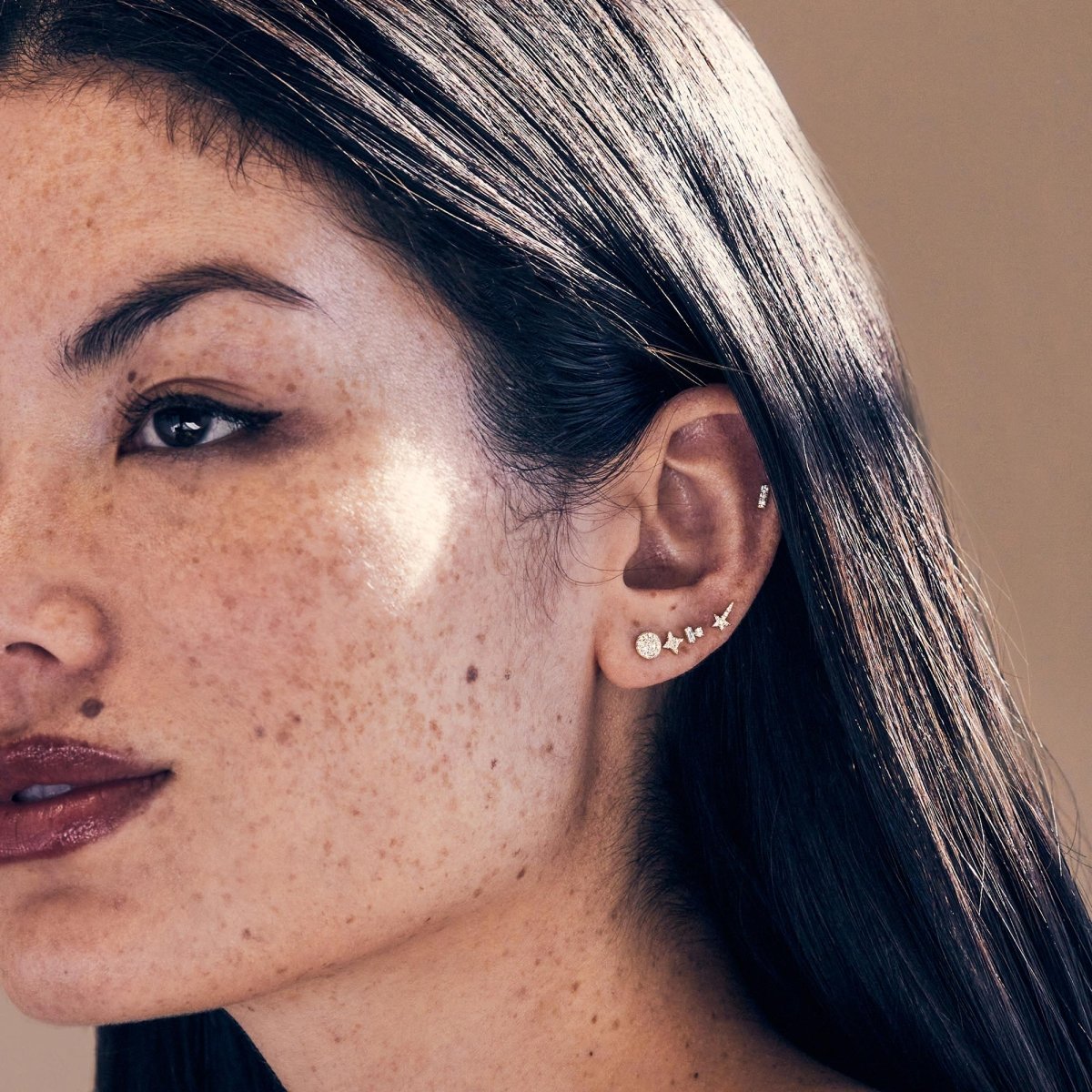 14K gold diamond star studs styled in an ear stack, shown on a model's lobe