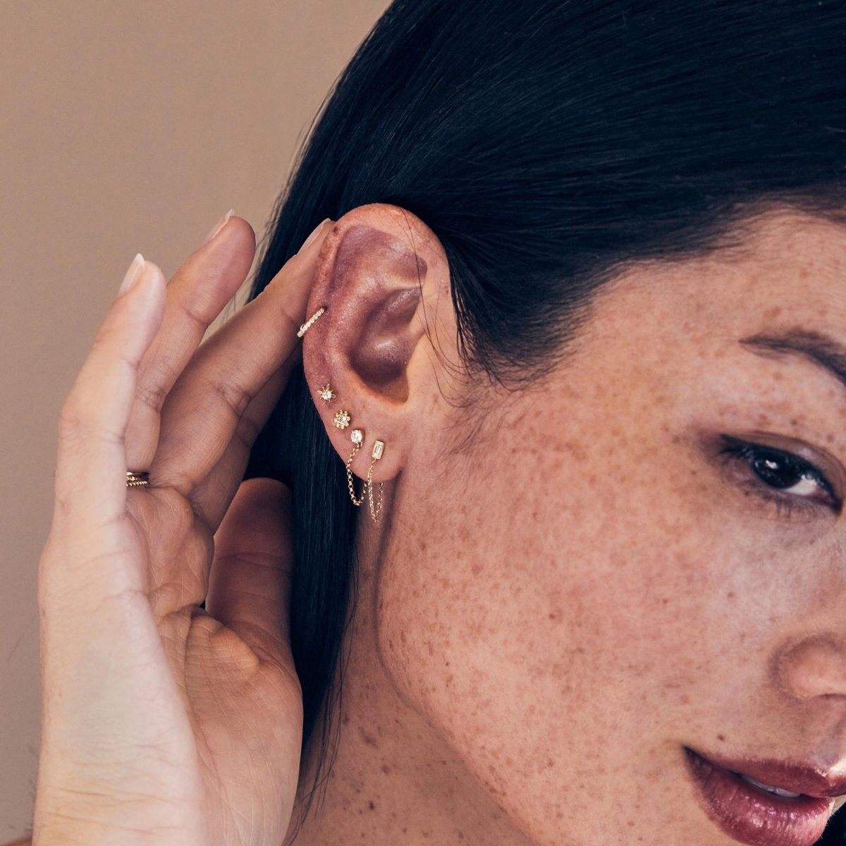 14K gold baguette diamond chain stud, shown in a model's lobe with a draping chain