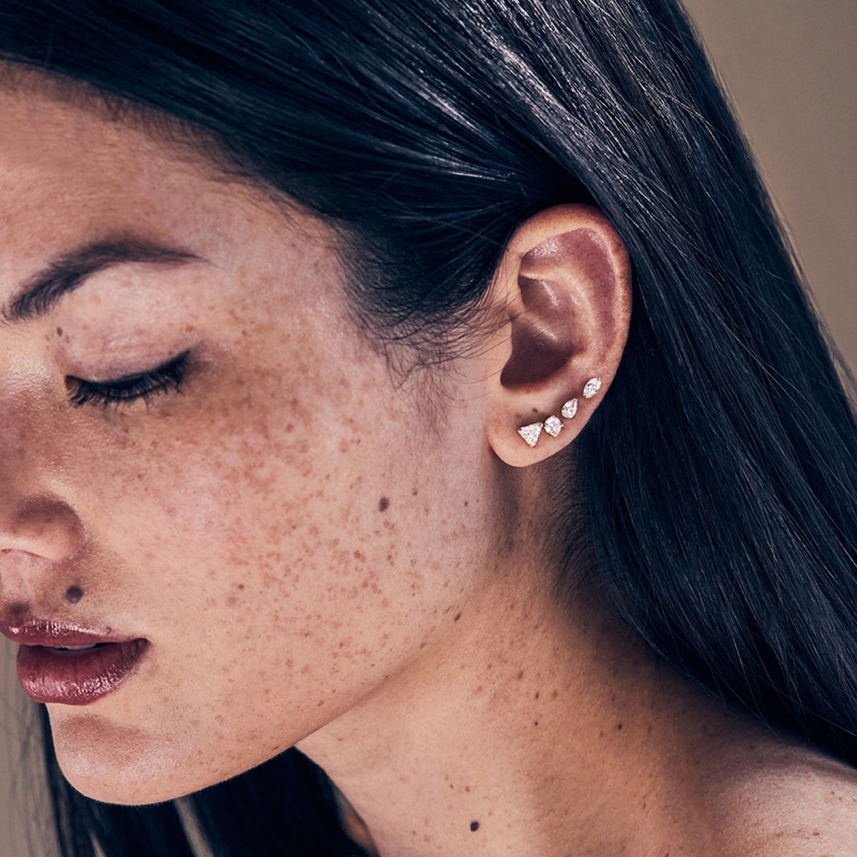 Gold vermeil pavé triangle studs shown stacked on a model's lobe with dark hair