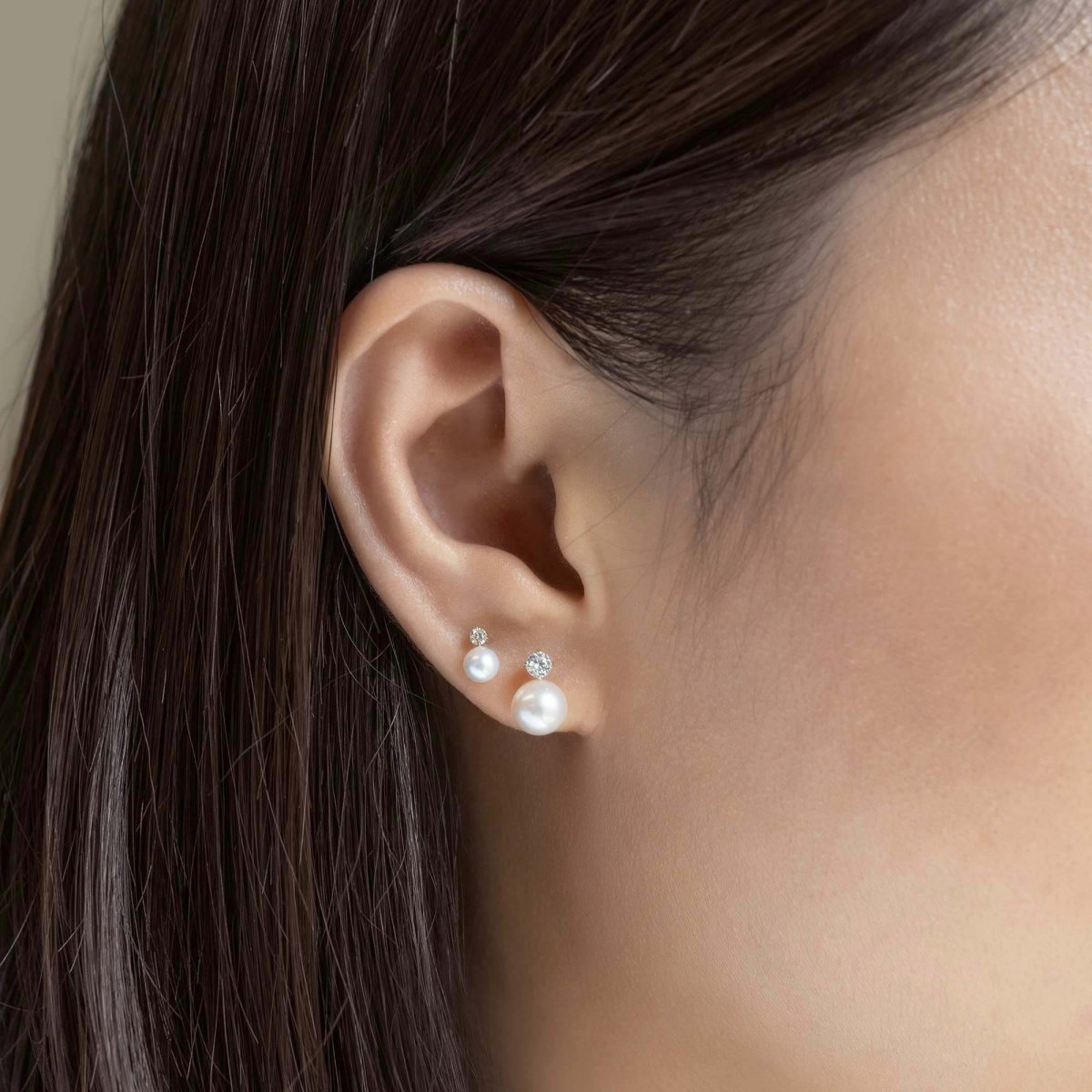 14K white gold pearl and clear-stone stud shown close up on a model's earlobe