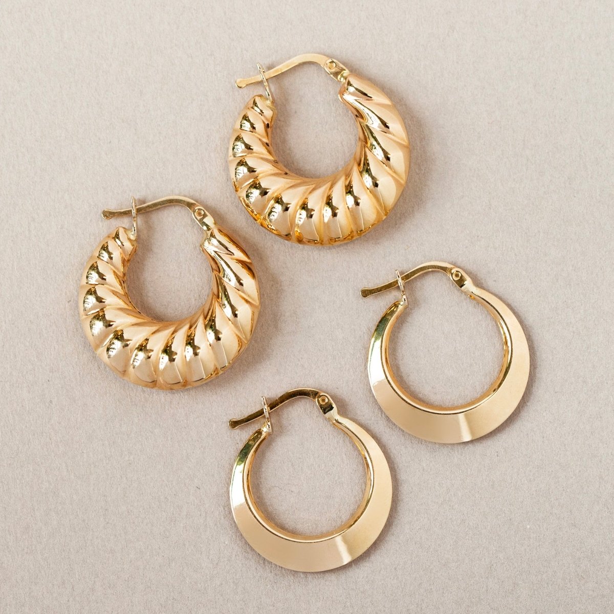 14K gold croissant bubble hoops shown beside plain hoops on a cream background
