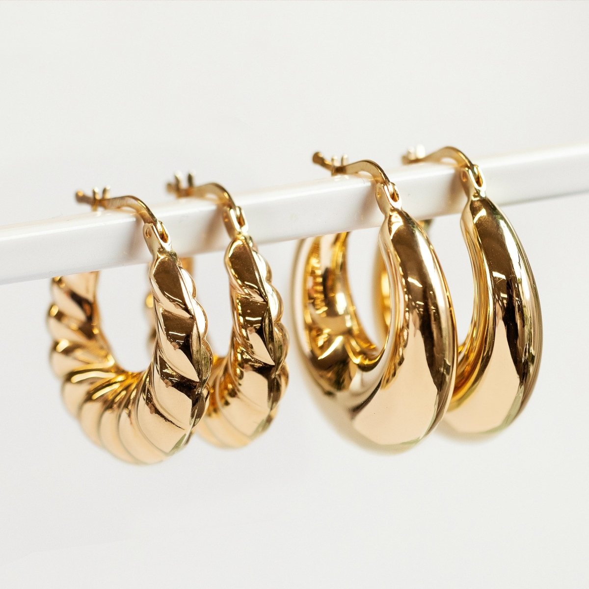 14K gold bubble hoop earrings, twisted and smooth styles, hung on a white bar