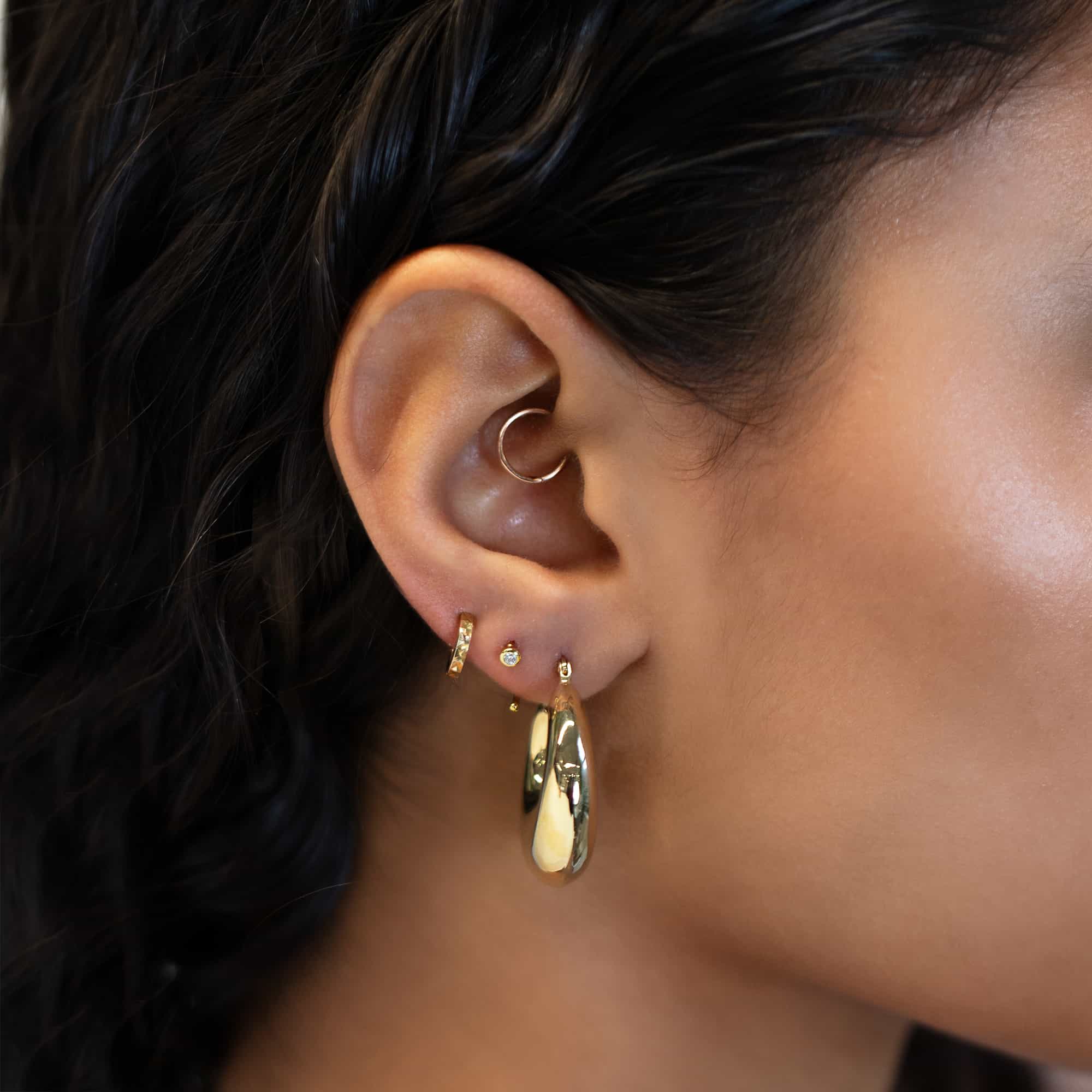 Gold vermeil white zirconia huggie earrings styled with hoops in a lobe stack on a model's ear