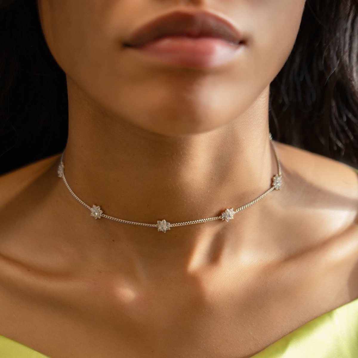 Sterling silver white zirconia choker with pavé flower stations, shown on a model's neckline