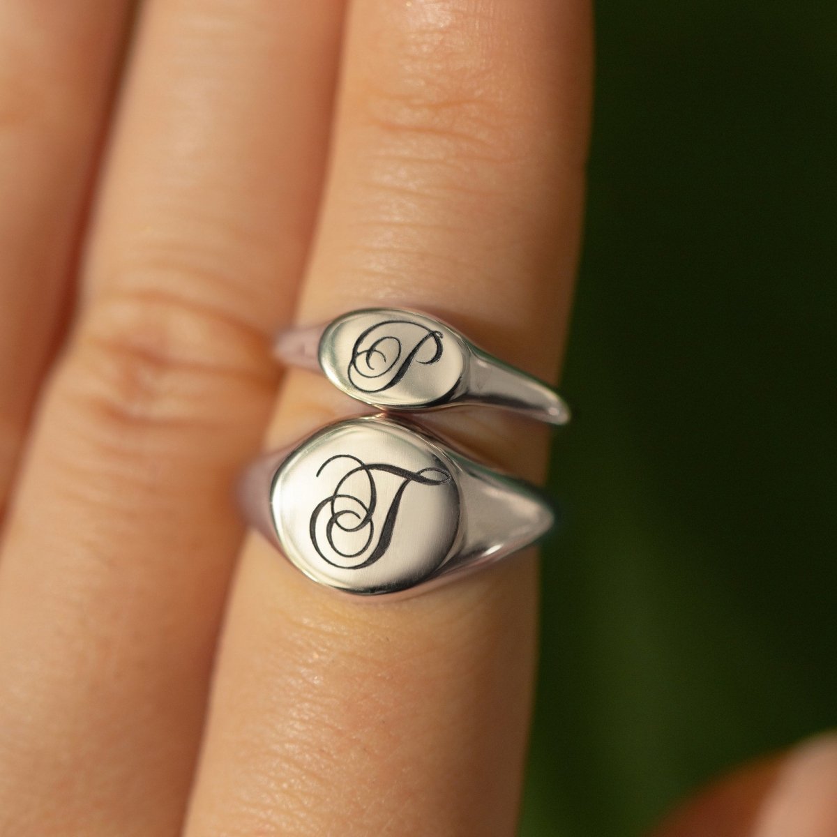 Sterling silver oval signet rings engraved with initials, shown stacked on a model's finger