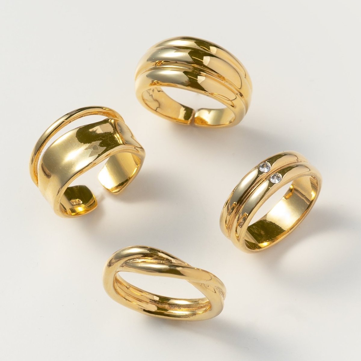 Four gold rings grouped together, including a gold vermeil double-band ring with two small white zirconia stones