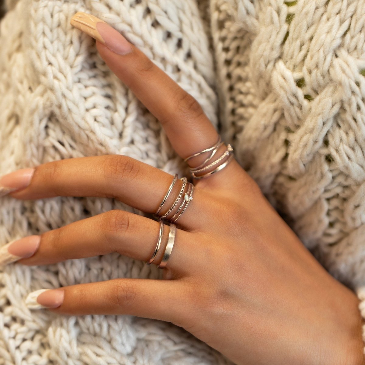 Sterling silver double band ring stacked on a hand, shown on a model's fingers against a sweater