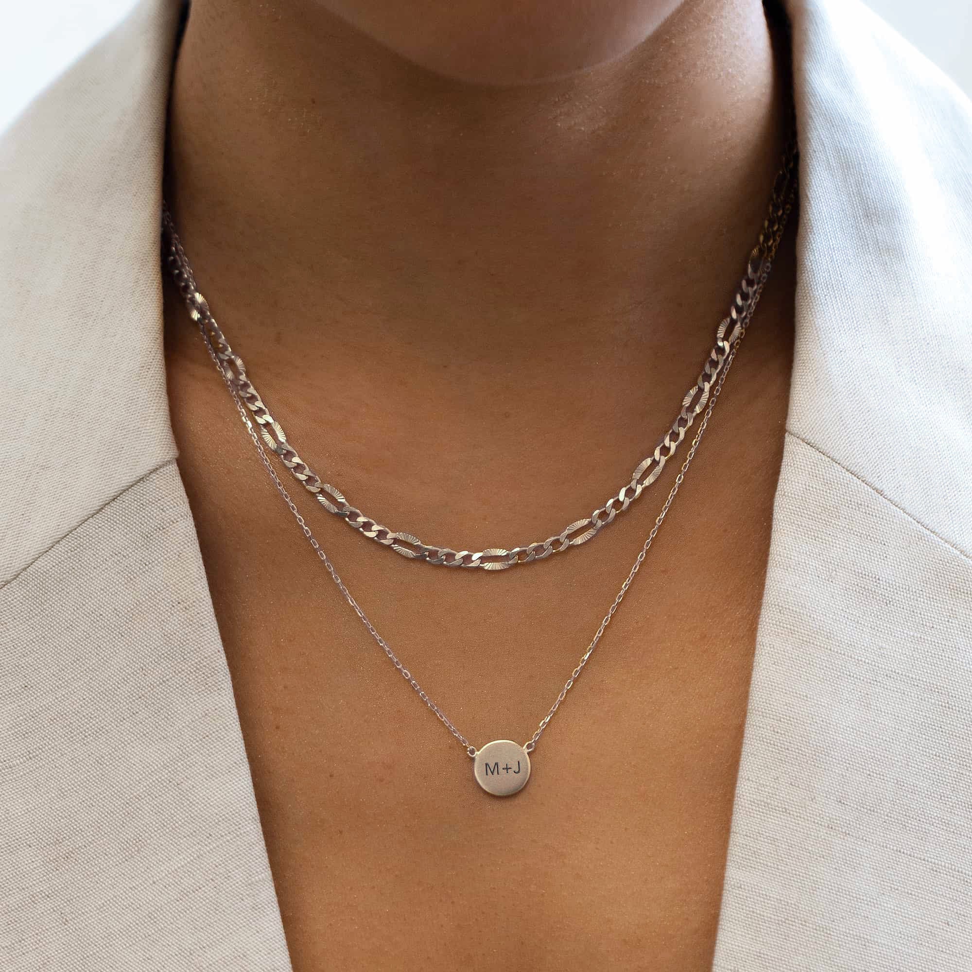 Sterling silver engravable disc necklace engraved with initials, layered on a model's neckline