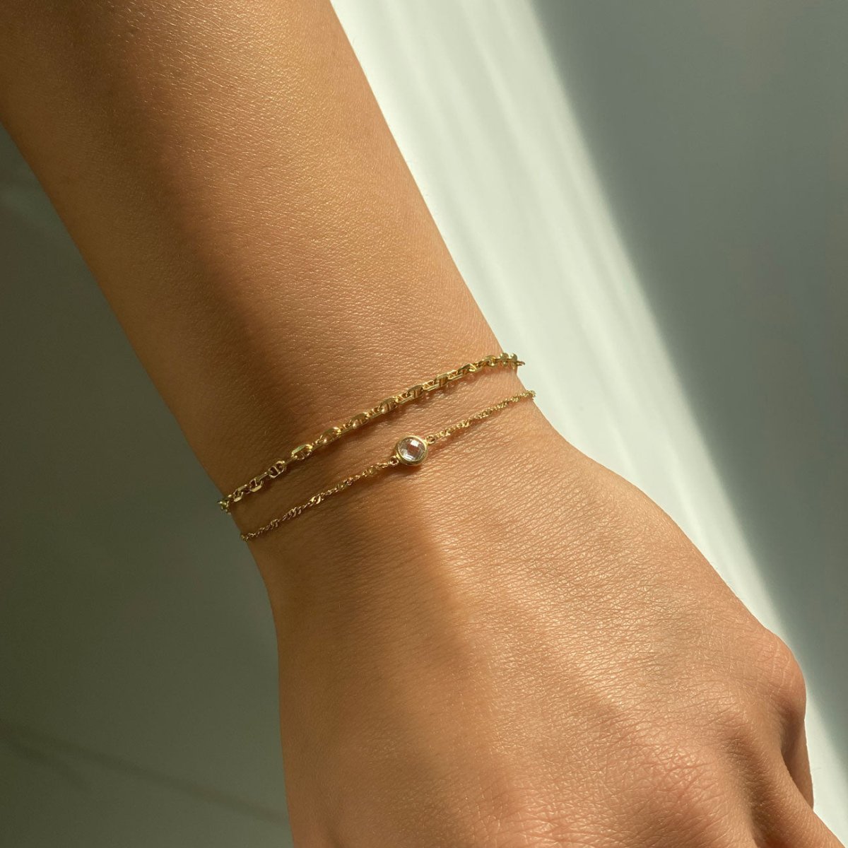 Gold vermeil Singapore chain bracelet with a clear bezel stone, shown on a model's wrist