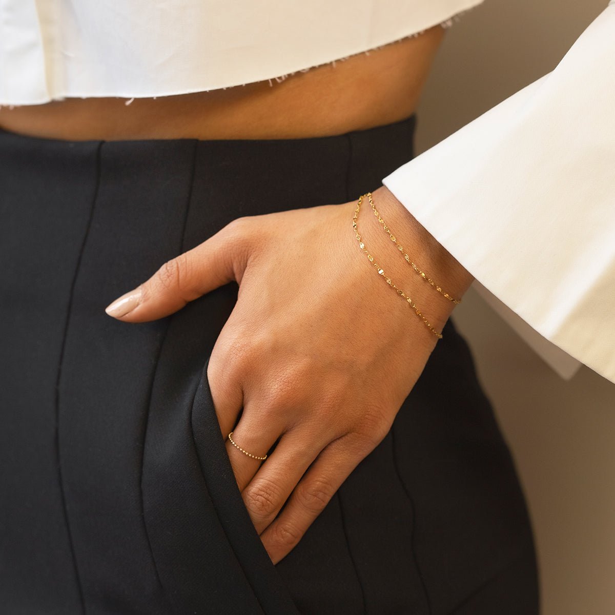 Gold vermeil layered mirror-link chain bracelet set shown on a model's wrist by a pocket