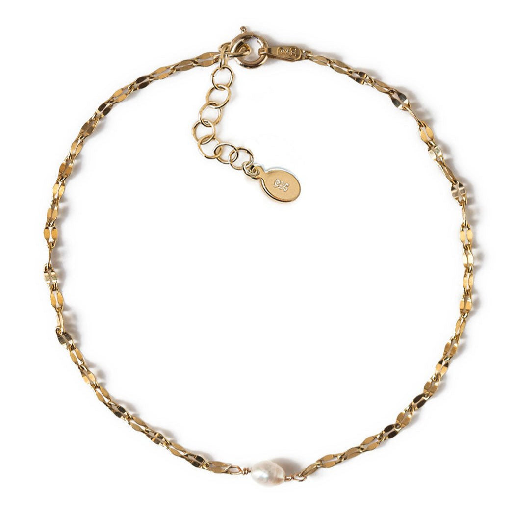 Gold vermeil mirror-link chain bracelet with a single pearl, laid on a white background