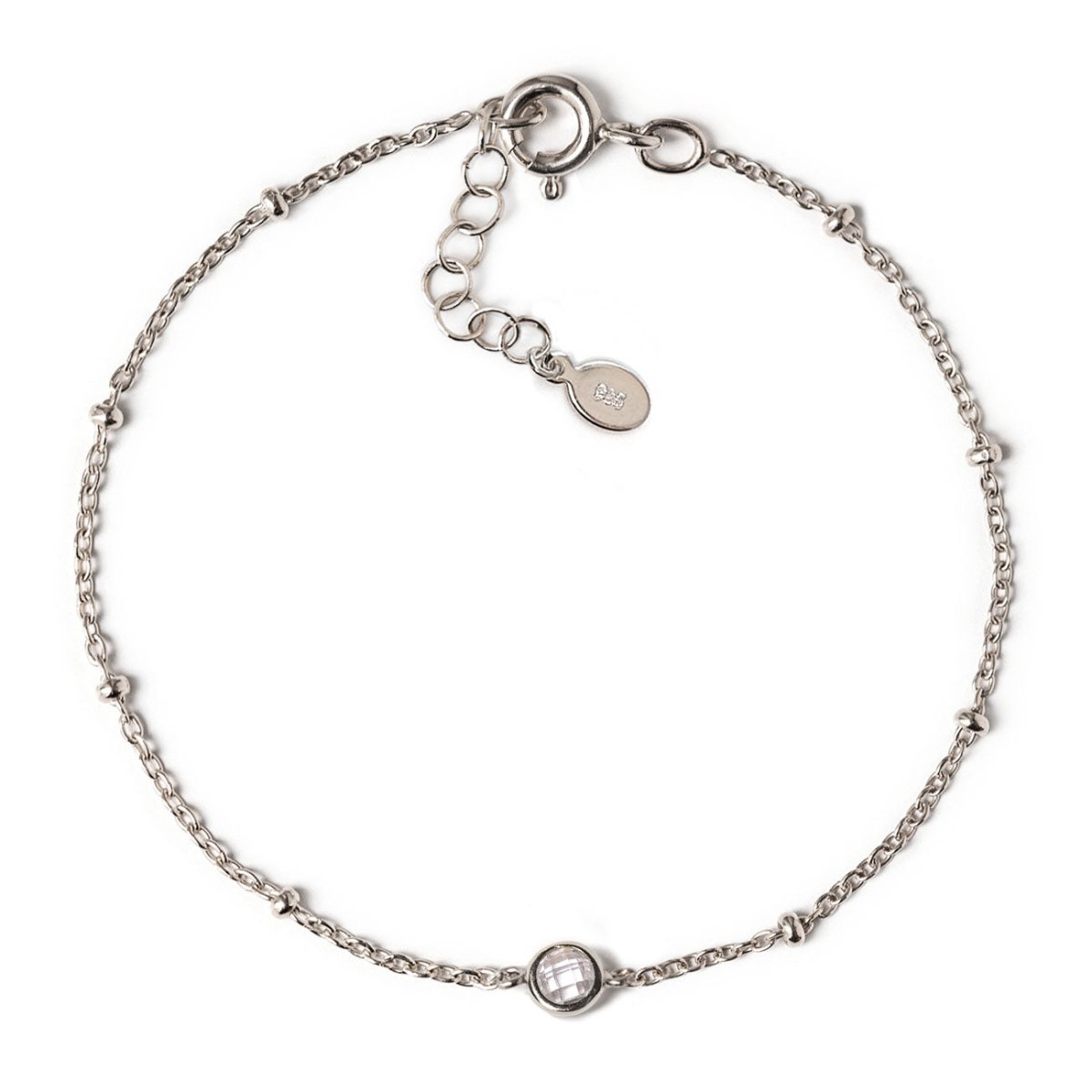 Sterling silver satellite chain bracelet with a single round clear stone, laid on a white background