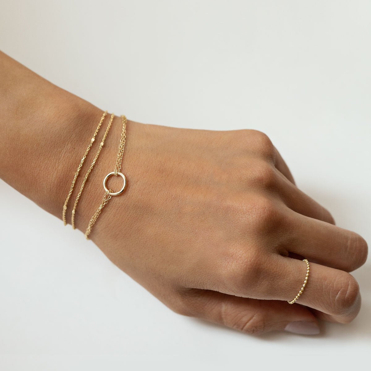 Gold vermeil layered chain bracelet with an open circle charm, shown on a model's wrist