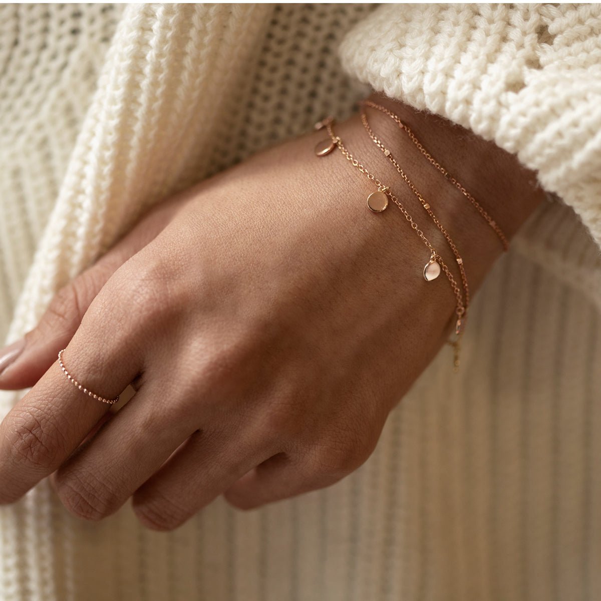 Rose gold vermeil disc dangle bracelet shown layered on a model's wrist