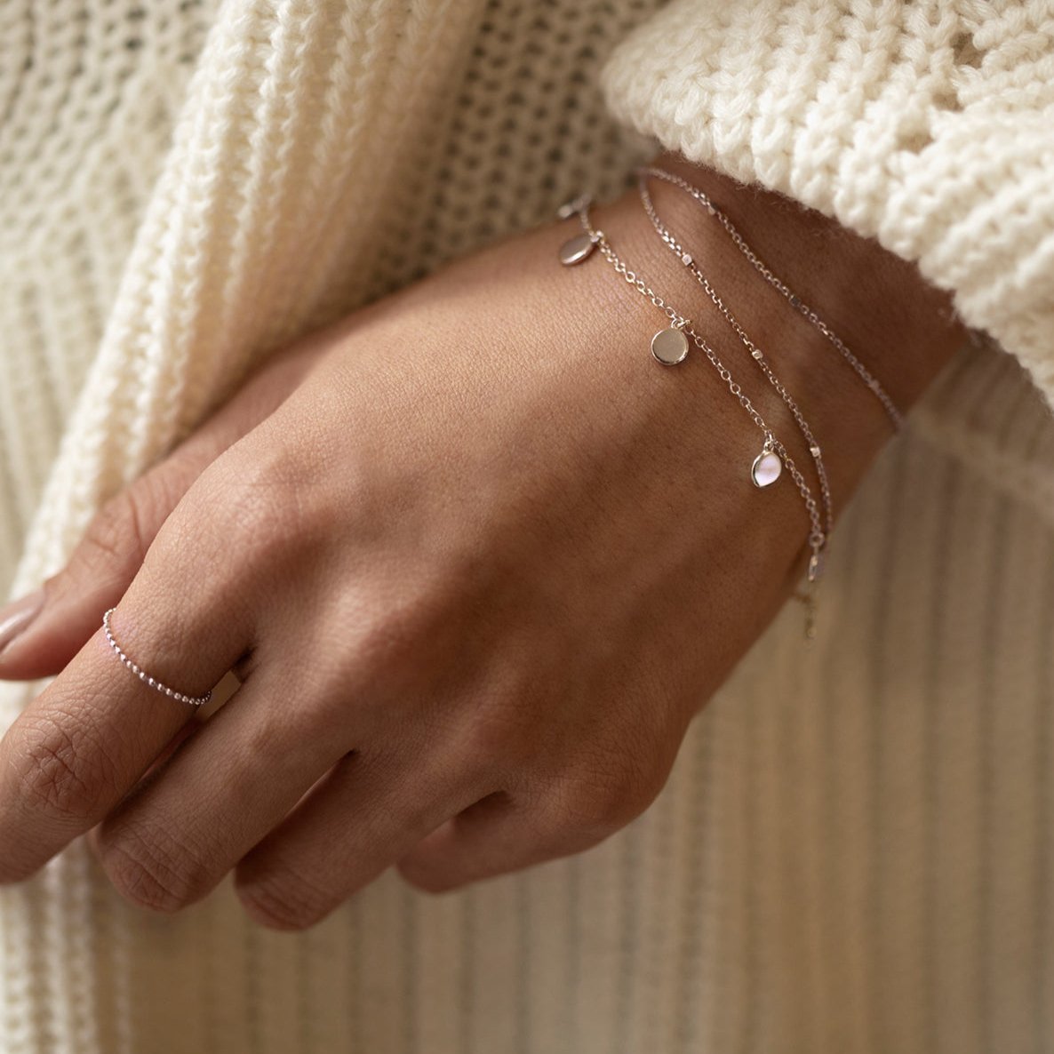 Sterling silver disc dangle bracelet shown layered with another chain on a model's wrist