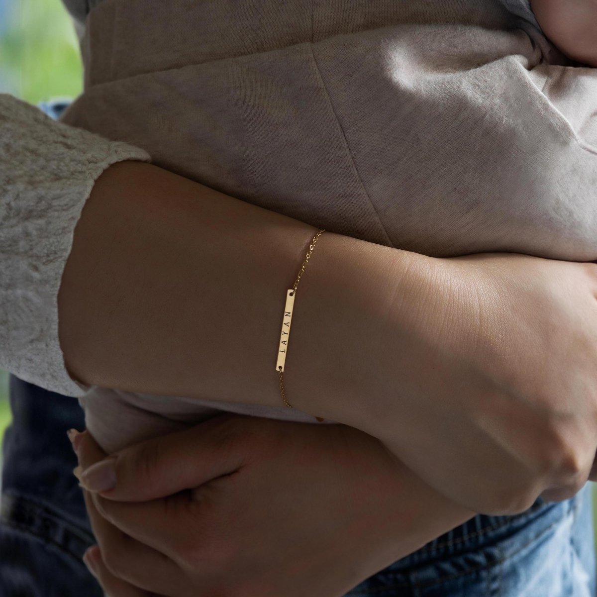 Gold-filled thin bar bracelet engraved with a name, shown on a model's wrist
