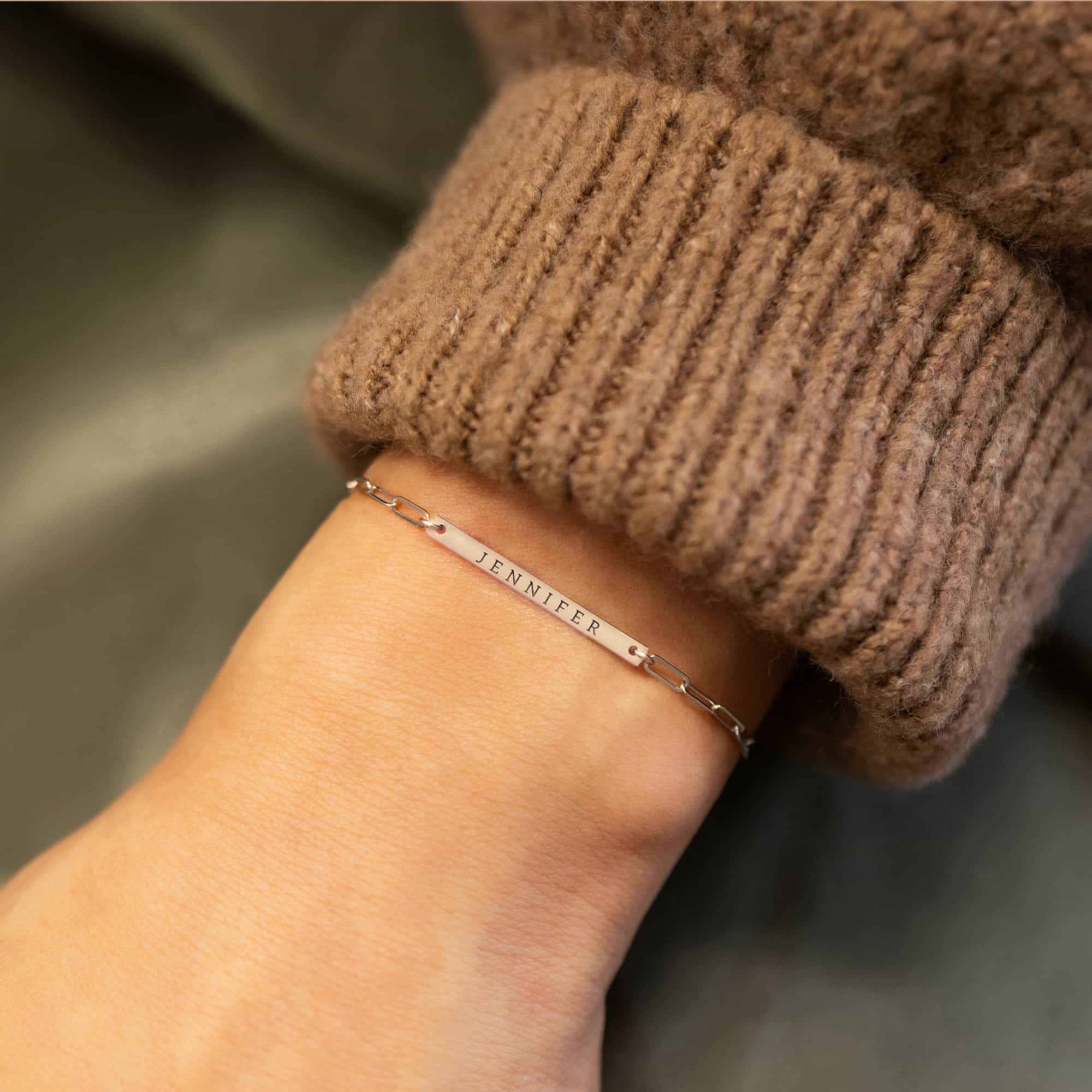 Sterling silver thin bar paperclip chain bracelet engraved with a name, on a model's wrist