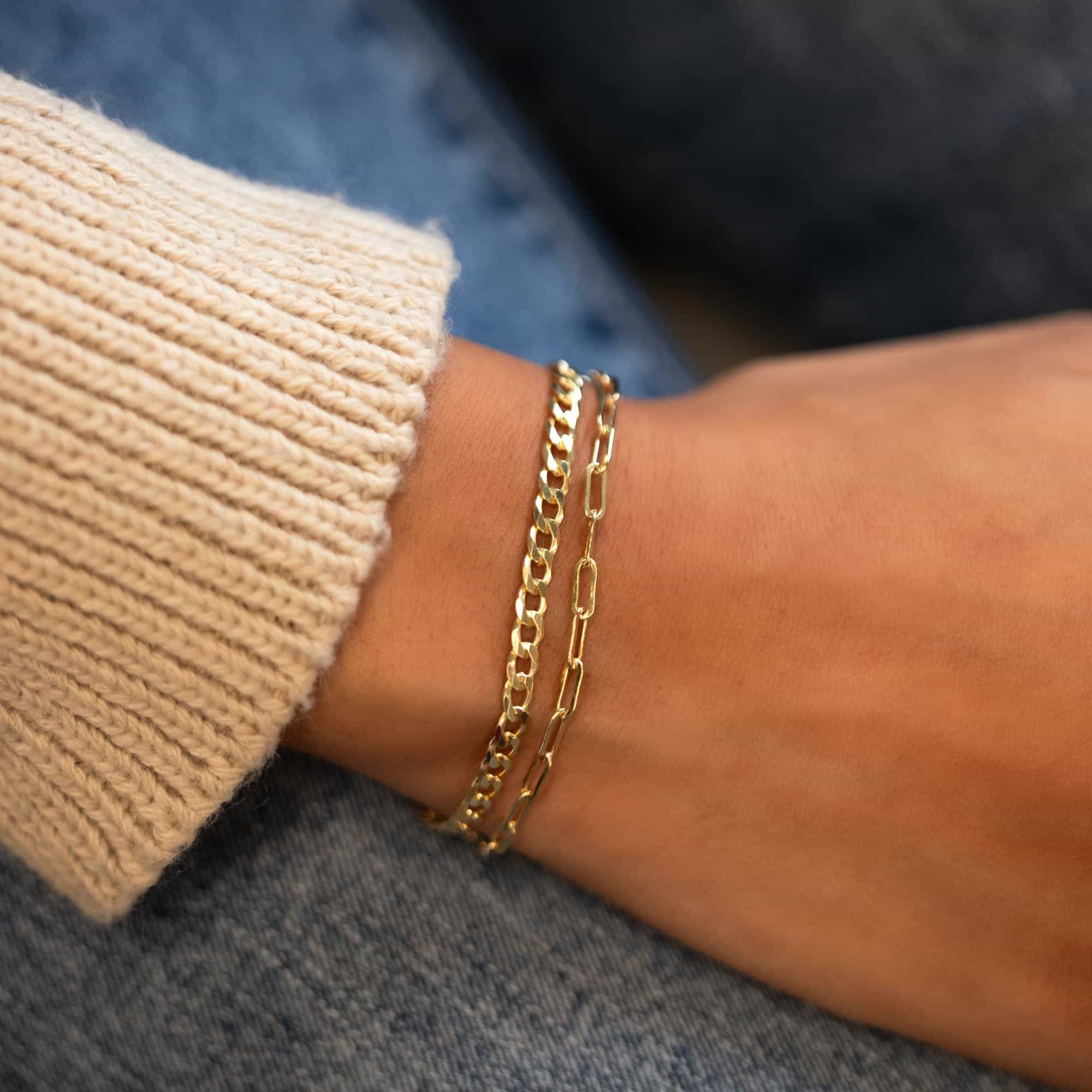 Gold-filled paperclip chain bracelet layered with a curb chain, shown on a model's wrist