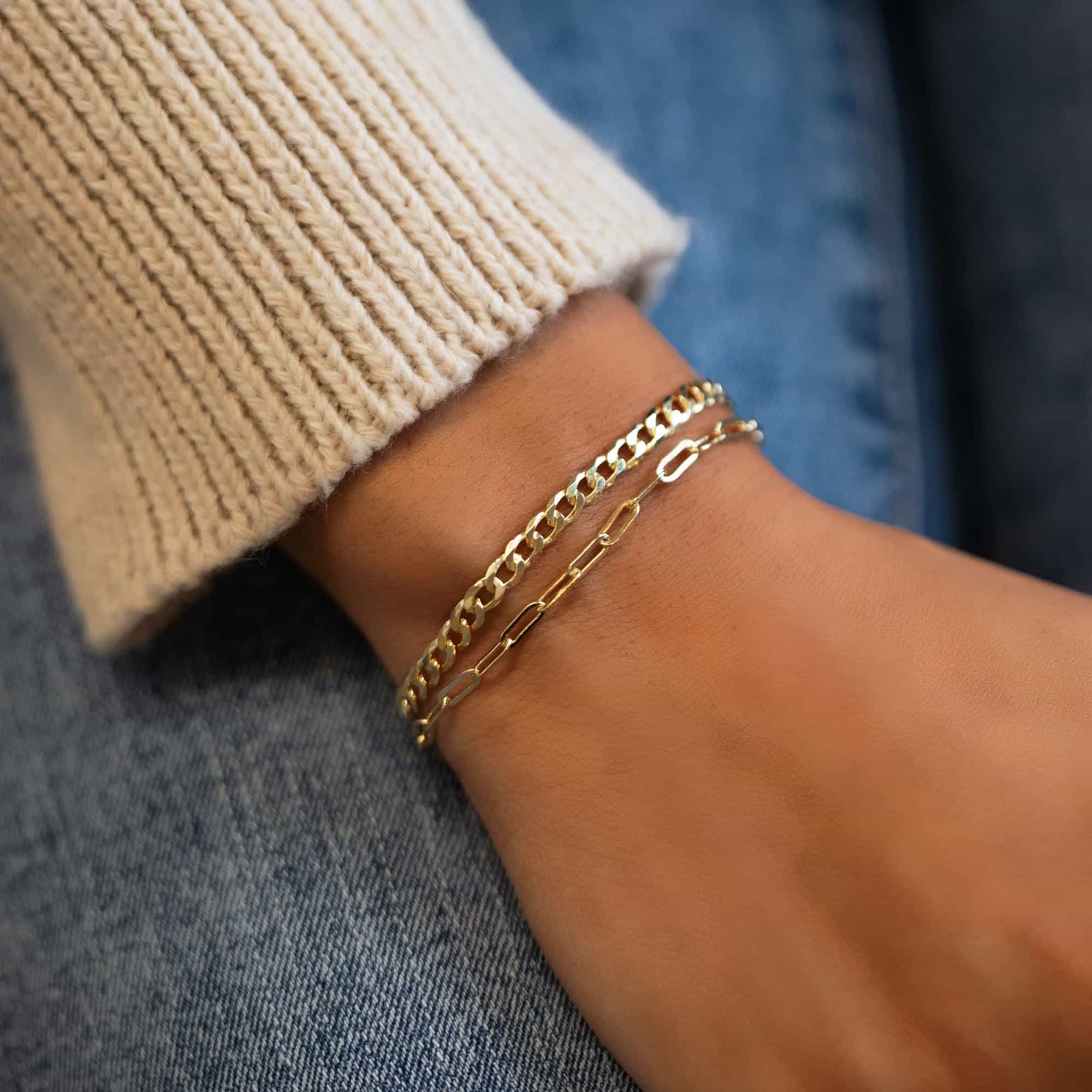 Gold vermeil Cuban curb chain bracelet stacked with a silver chain, shown on a model's wrist