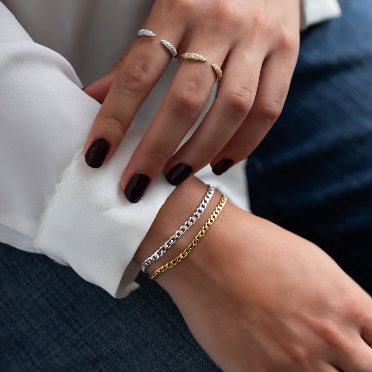 Sterling silver Cuban curb chain bracelet next to a gold curb chain, shown on a model's wrist