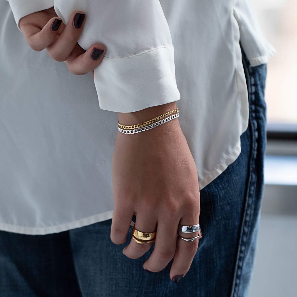 Gold vermeil Cuban curb chain bracelet stacked with a silver chain, shown on a model's wrist