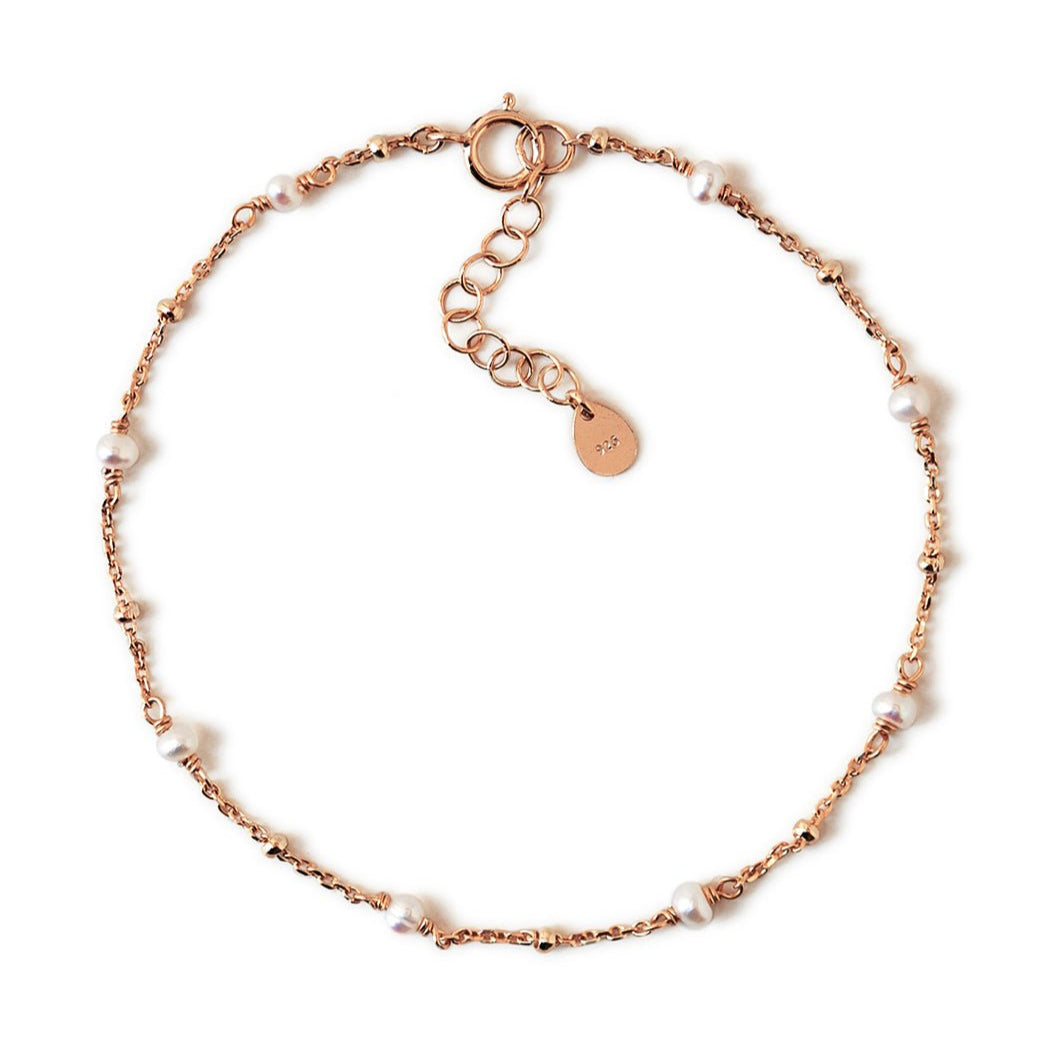 Rose gold vermeil satellite chain bracelet with small white pearls, laid on a white background