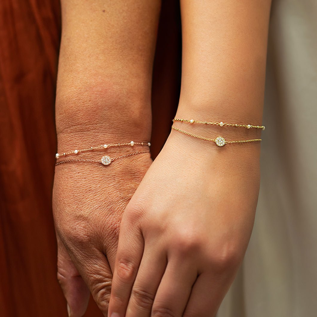 Gold vermeil pearl chain bracelet shown stacked on a wrist with a delicate satellite chain