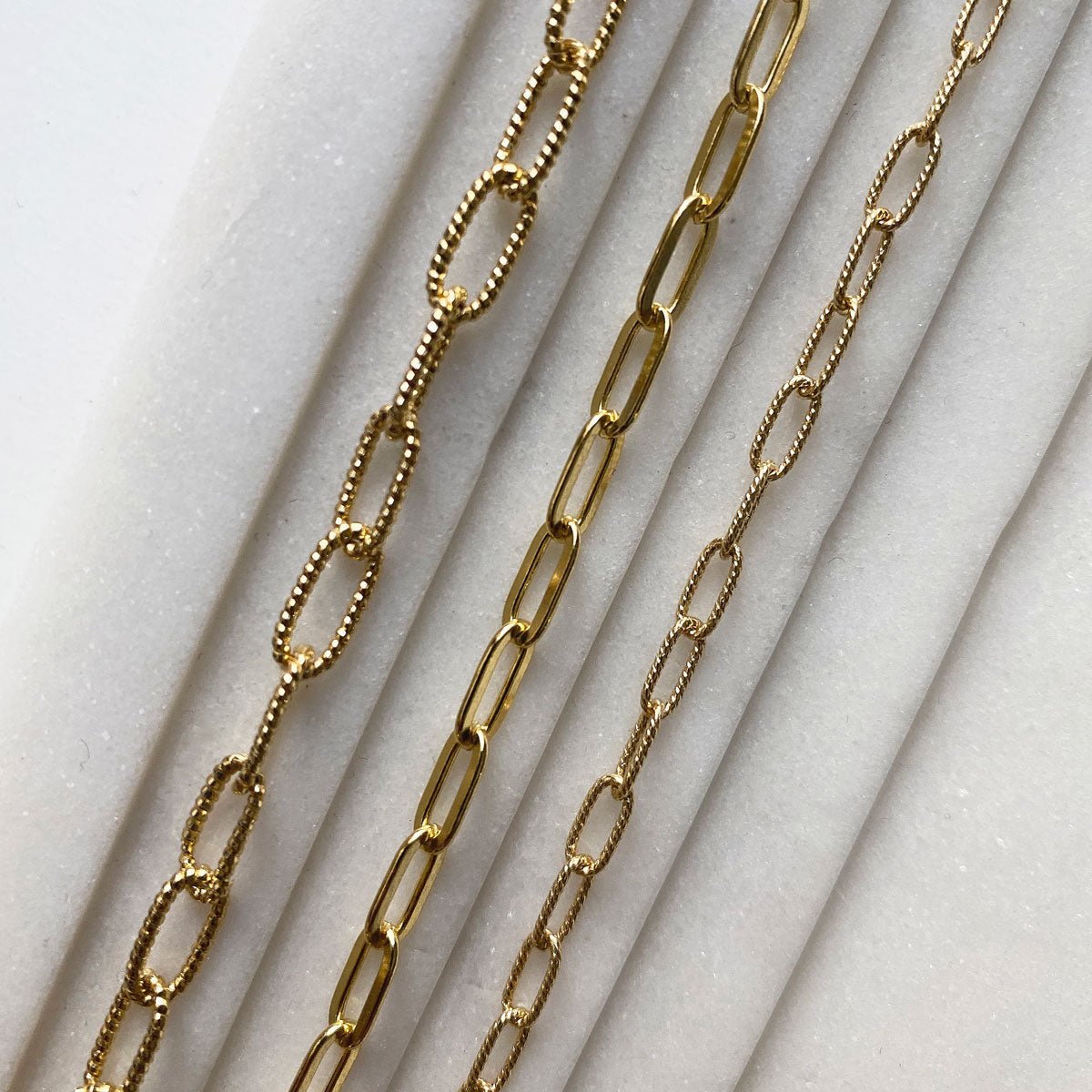 Gold vermeil oval link chain bracelet, close-up detail of the textured links on white marble
