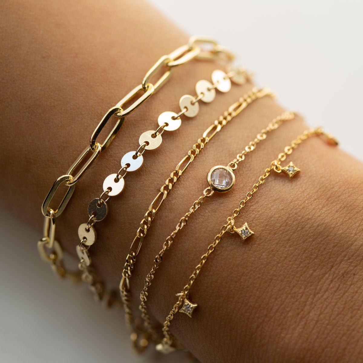 Gold vermeil star dangle bracelet stacked with a gold paperclip chain, shown on a model's wrist