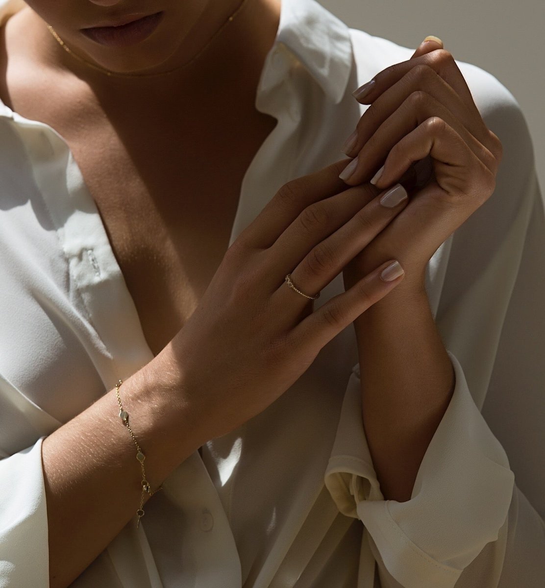 Sterling silver three-stone ring with clear stones, shown on a model's hand beside a station bracelet