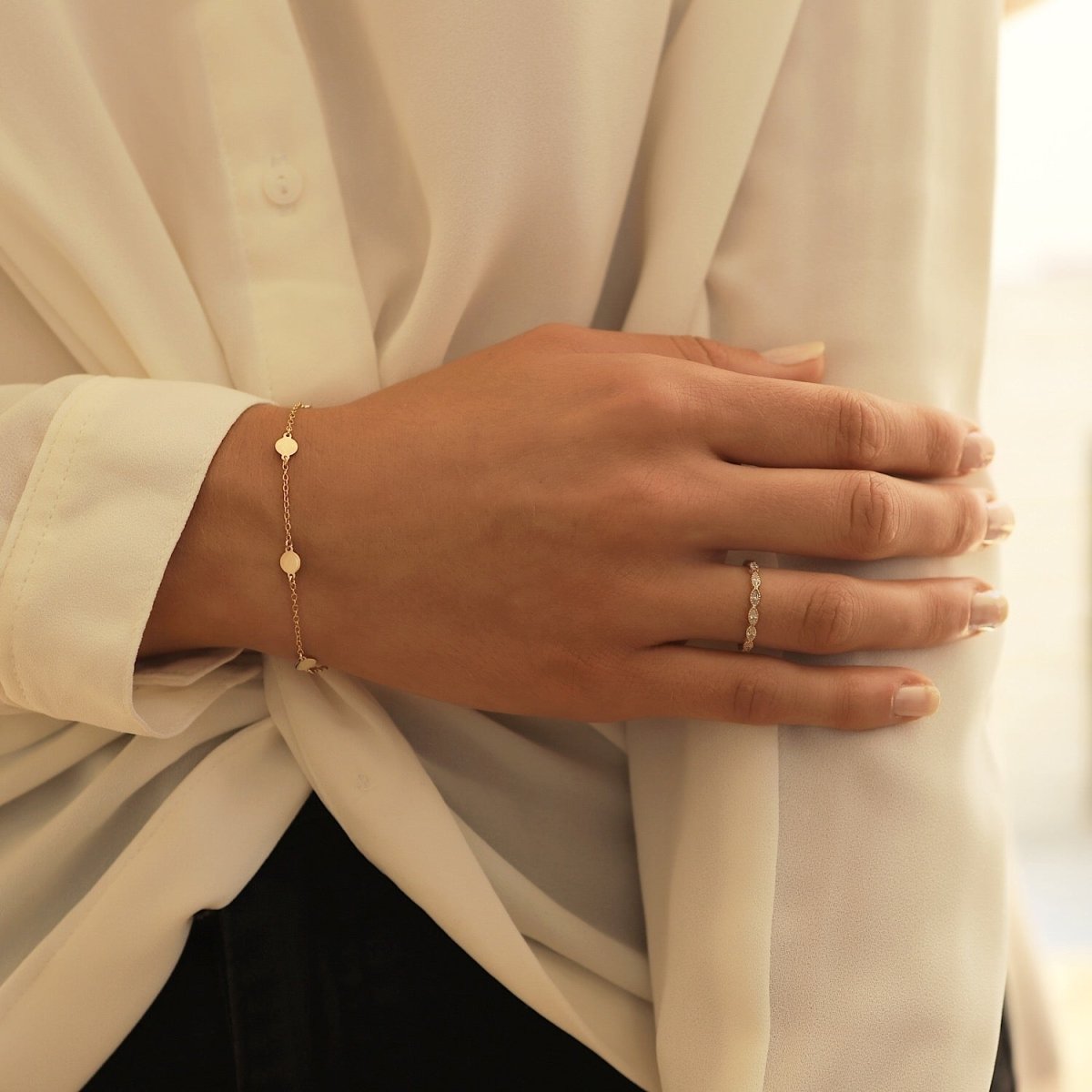 Gold vermeil round disc station bracelet shown on a model's wrist with a ring and white blouse