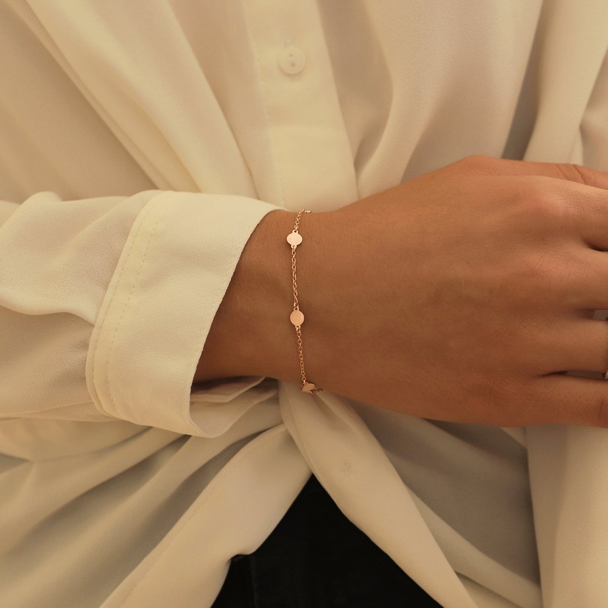 Rose gold vermeil round disc station bracelet shown on a model's wrist with a white blouse