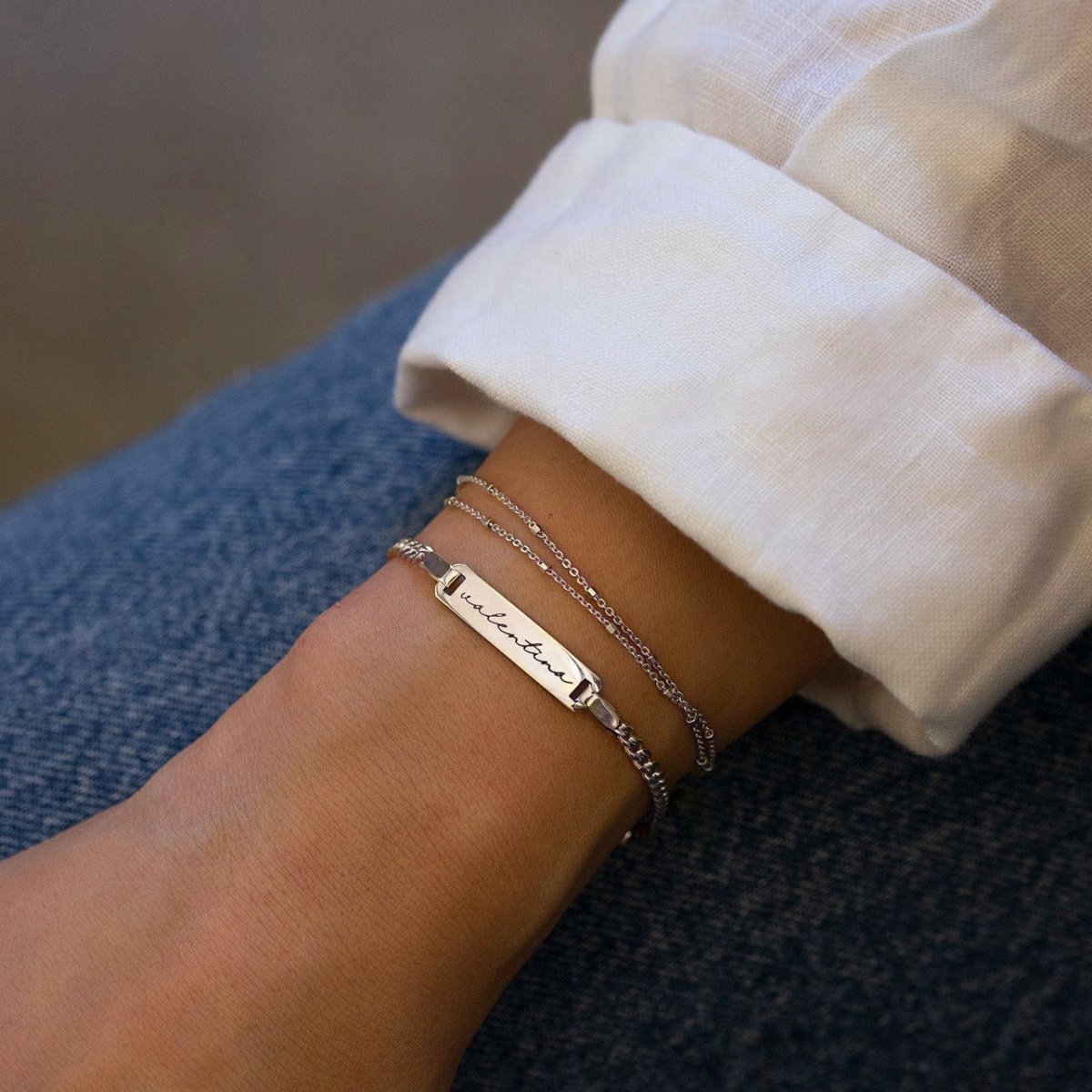 Sterling silver curb chain ID bracelet engraved with a name, shown on a model's wrist