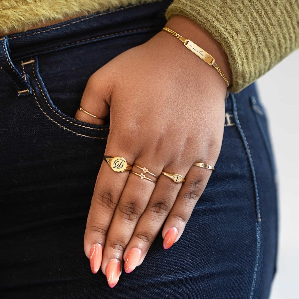 Gold vermeil oval signet ring engraved with an initial, shown on a model's hand