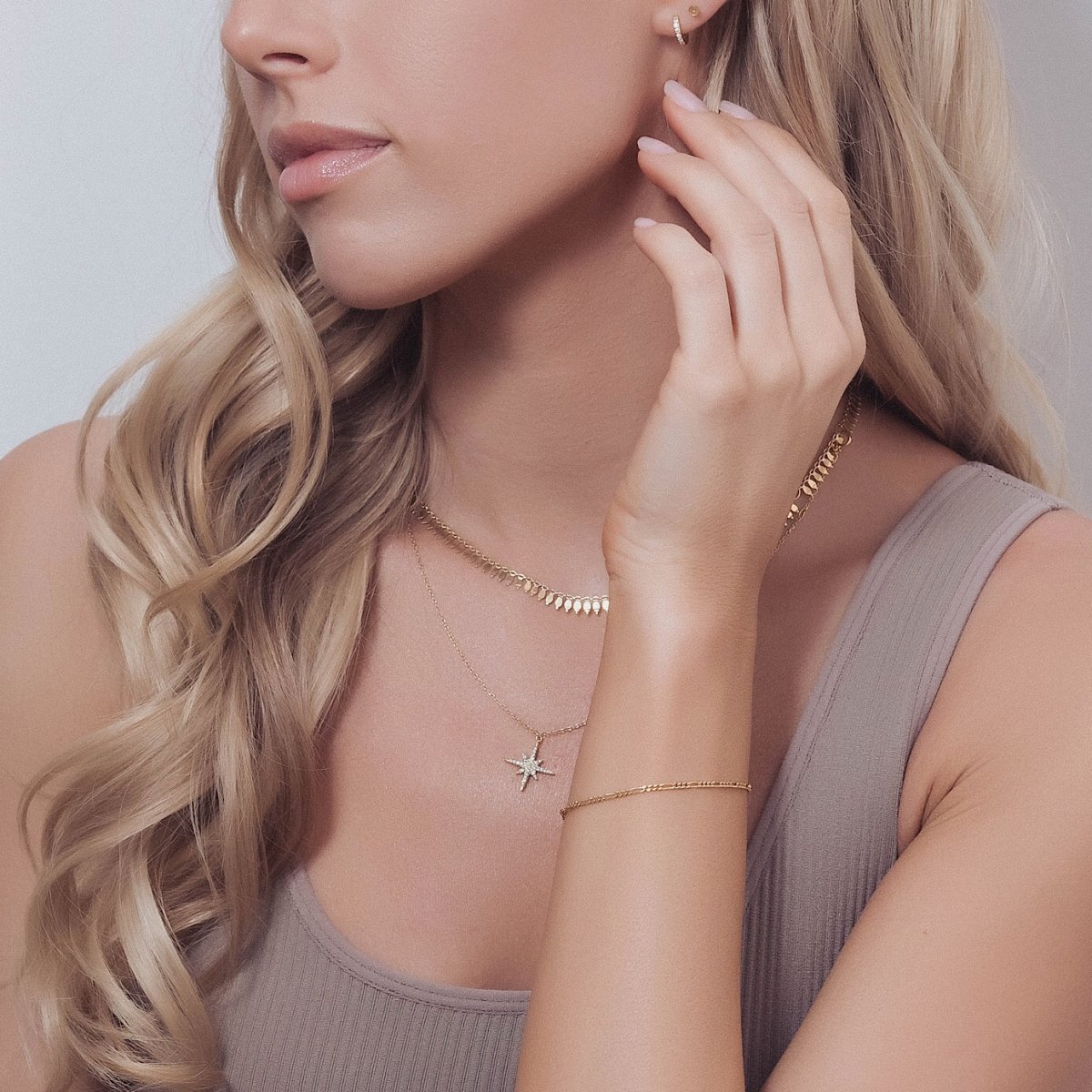 Gold vermeil Figaro chain bracelet shown on a model's wrist with a layered necklace and pendant