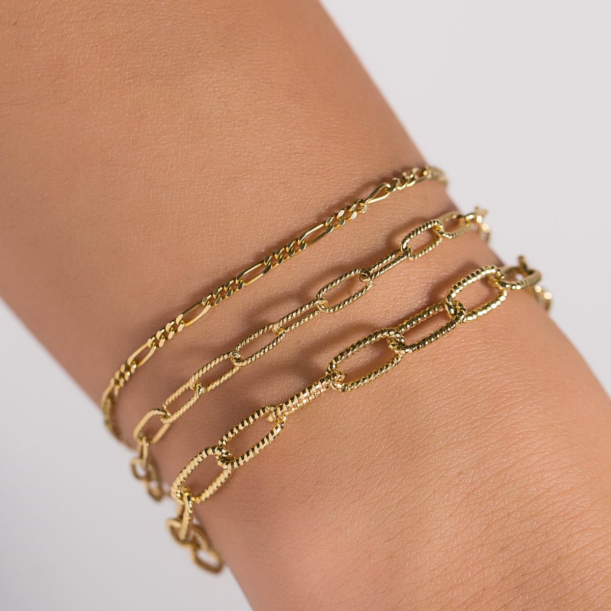 Gold vermeil chunky link chain bracelet layered with finer chains on a model's wrist
