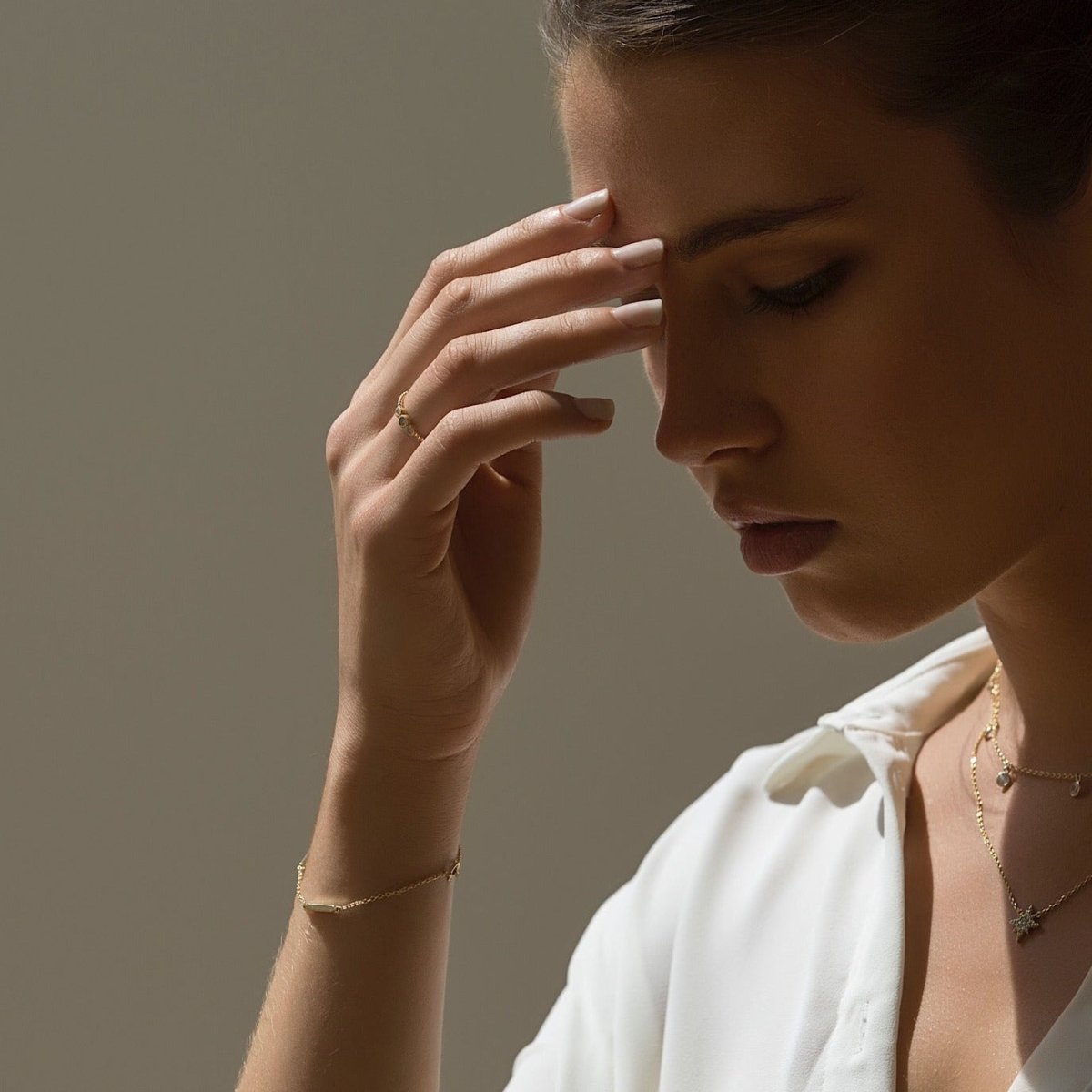 Gold vermeil eternity bar bracelet on a model's wrist, layered with delicate necklaces